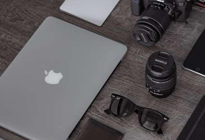 Desk with laptop, camera and sunglasses