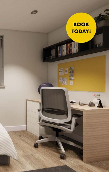 Bedroom workspace with wooden desk, gray mesh office chair, yellow bulletin board, shelf of books, globe and round 'BOOK TODAY!' badge.