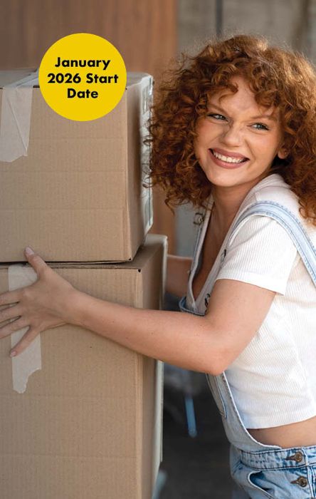 Woman with curly hair smiling while holding cardboard boxes. A yellow circle reads, "January 2026 Start Date."