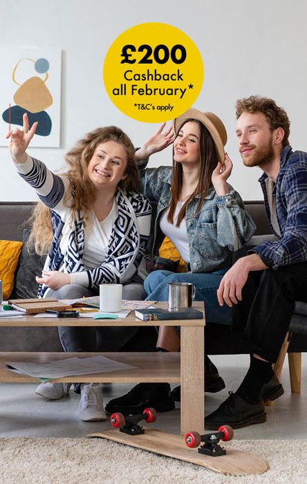 Three people smiling and gesturing peace signs while sitting on a couch, with a £200 cashback offer displayed above.