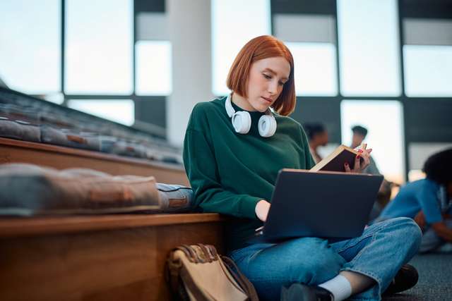 University student using her laptop while learning in lecture hall