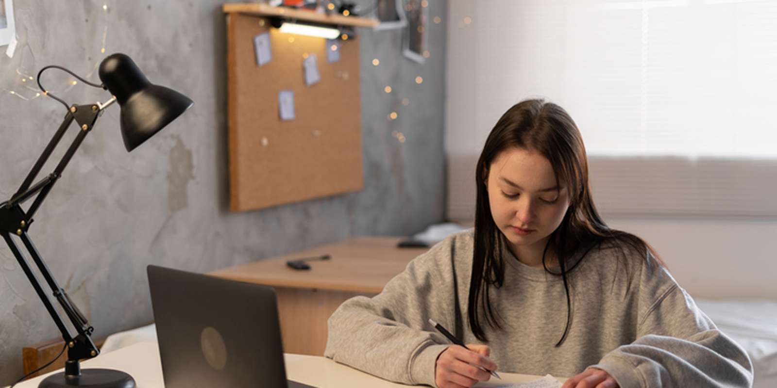 Student writing notes on desk in student accommodation