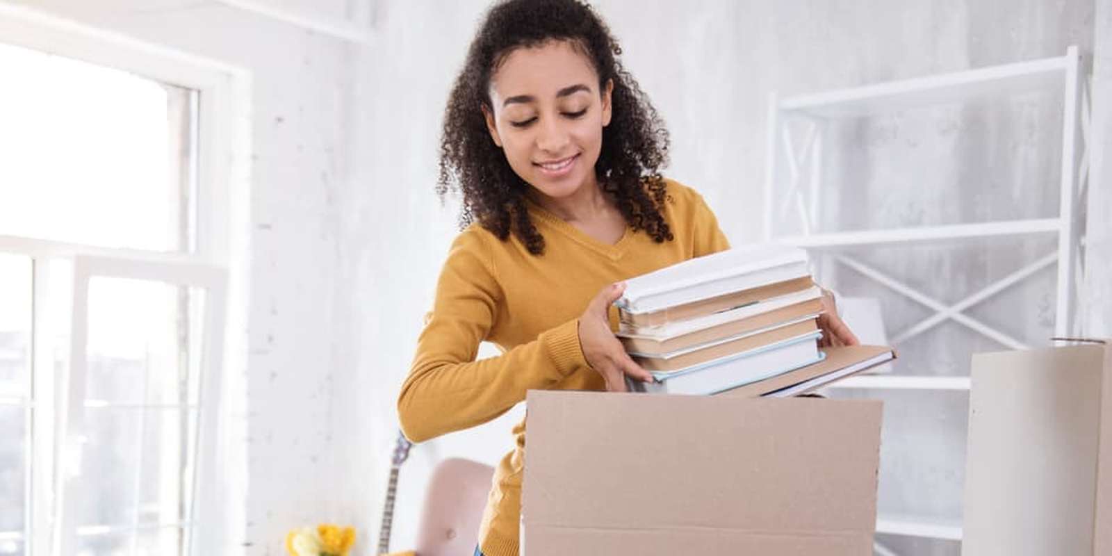 Girl student packing a box with books