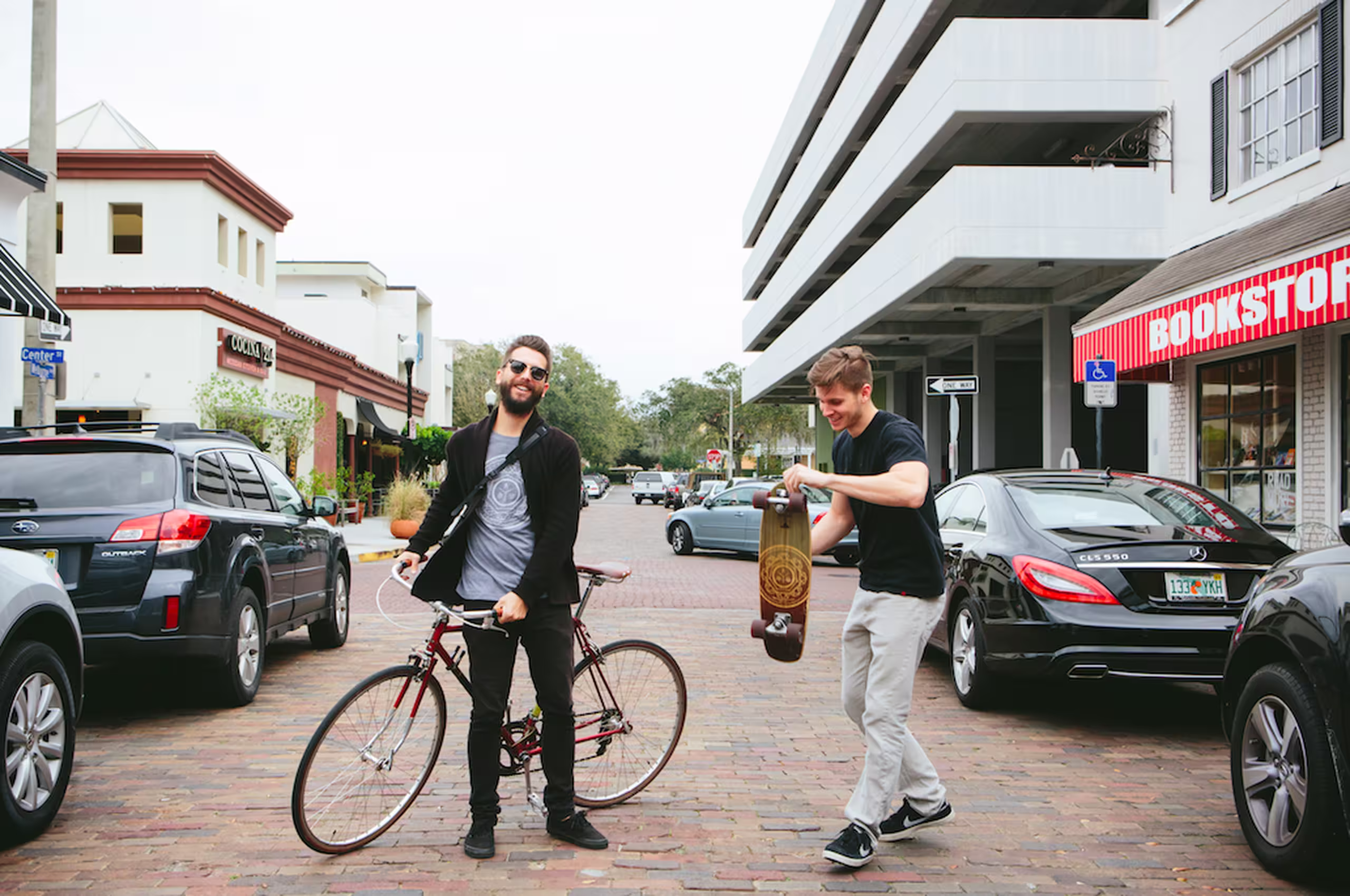 one person holding a bicycle and the other a skateboard