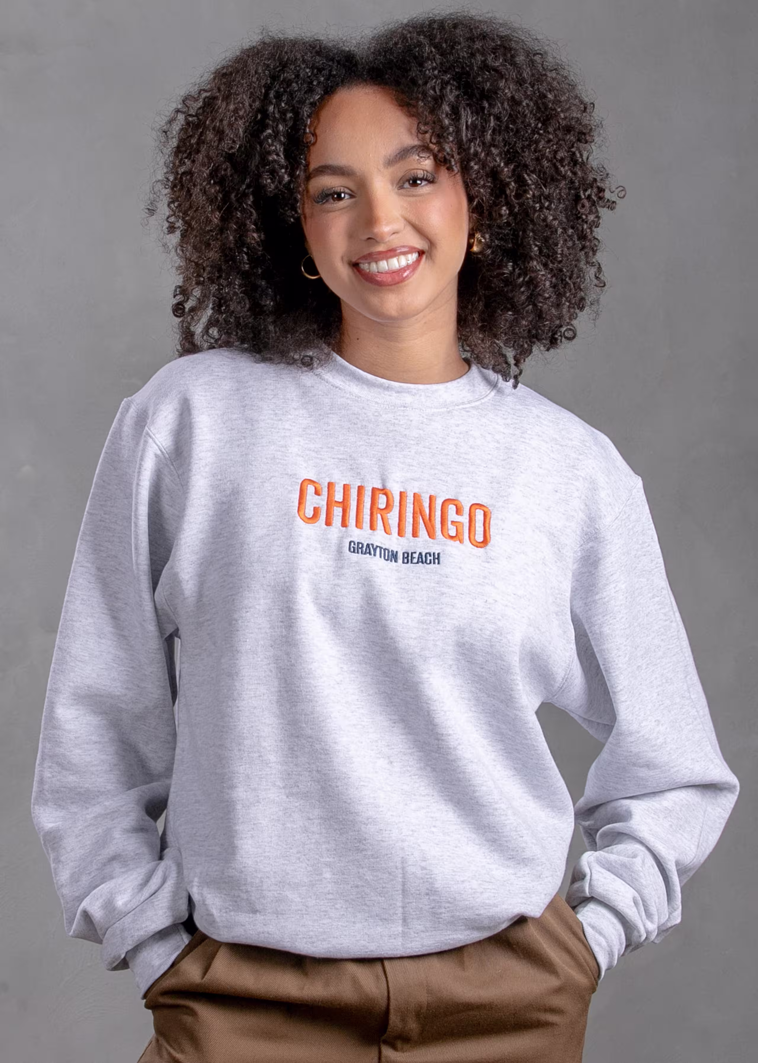 women wearing a white crewneck sweatshirt with the word Chiringo embroidered