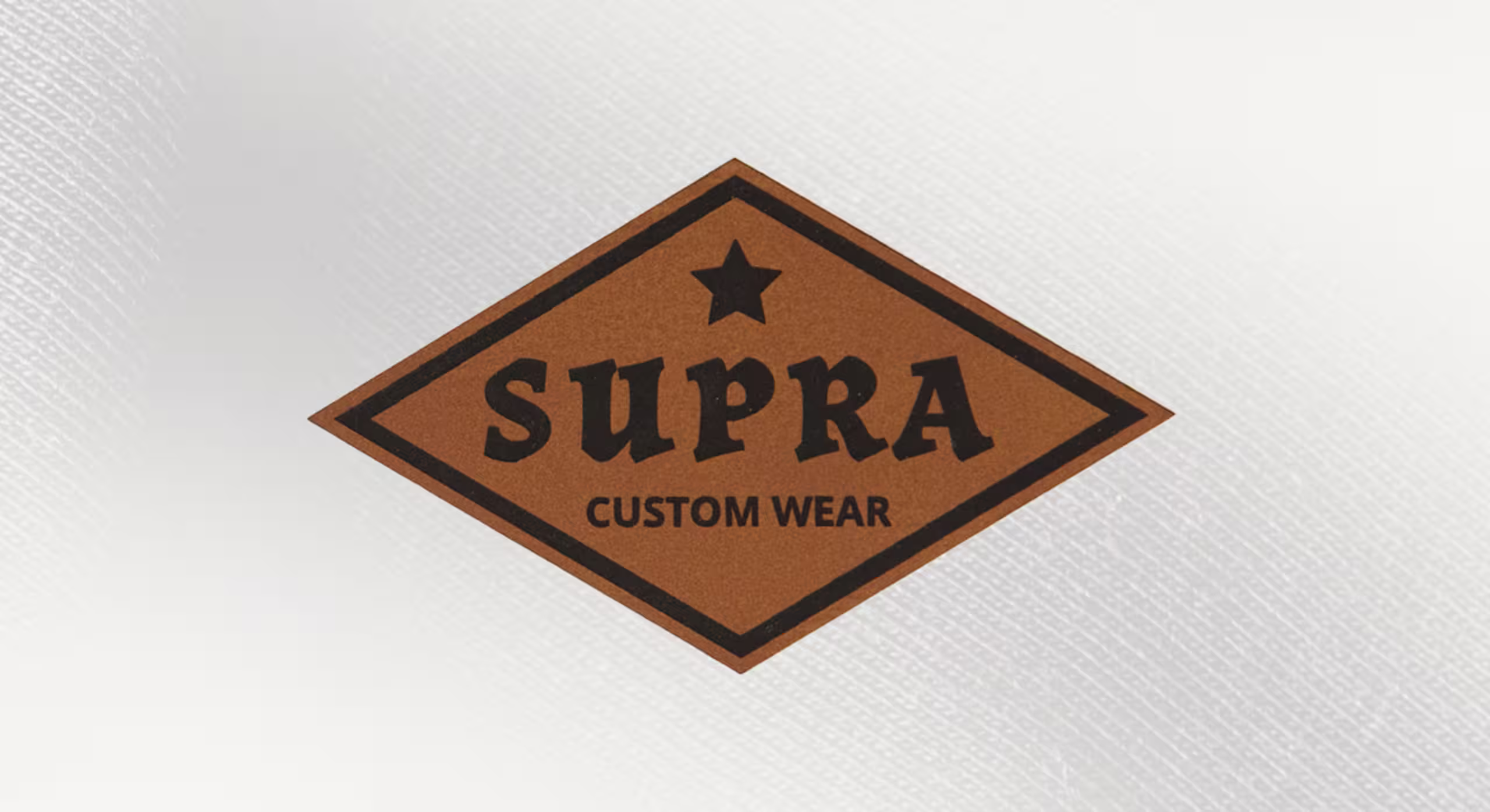 a faux chestnut patch in a diamond with the words supra custom wear