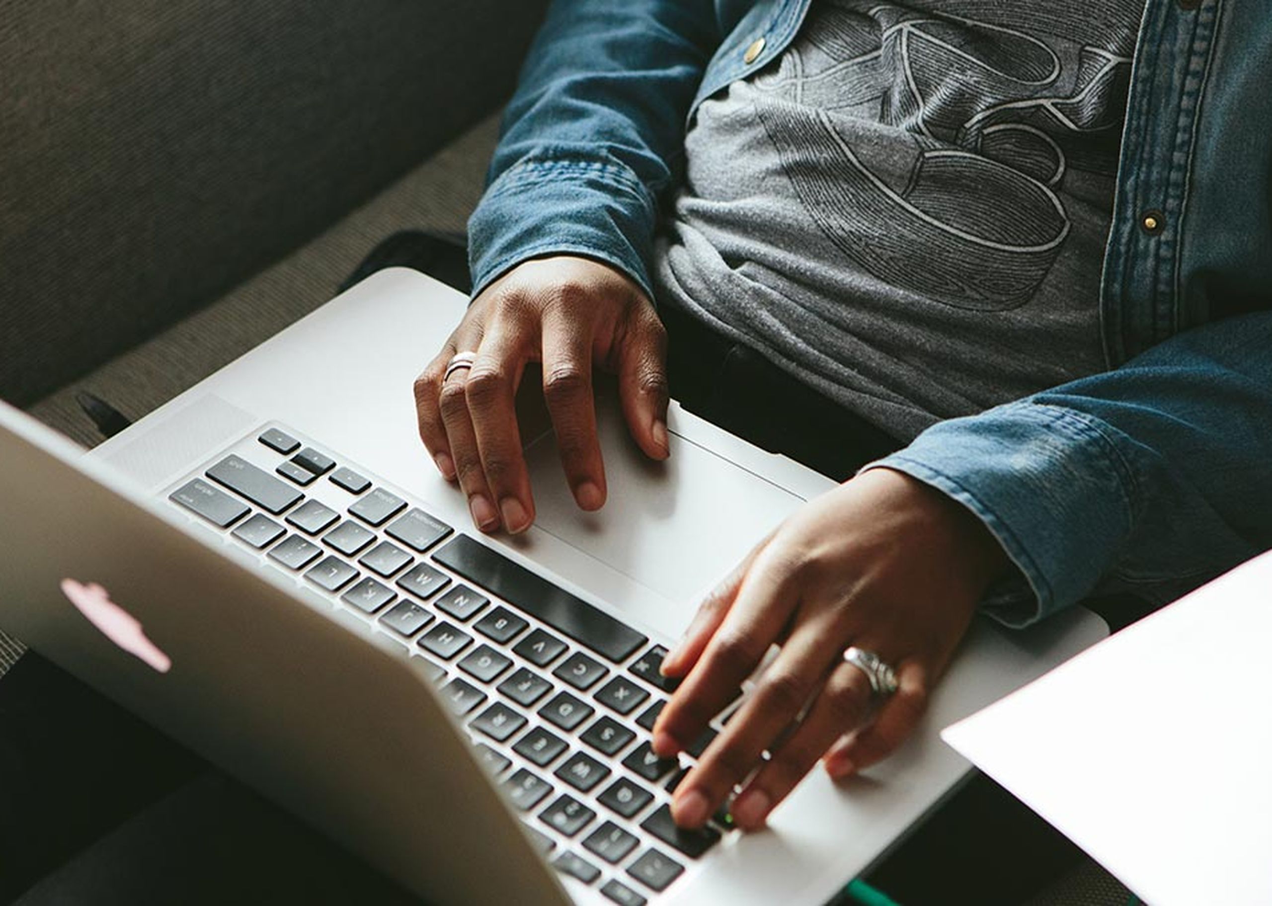 A man types on his laptop while wearing a custom t-shirt