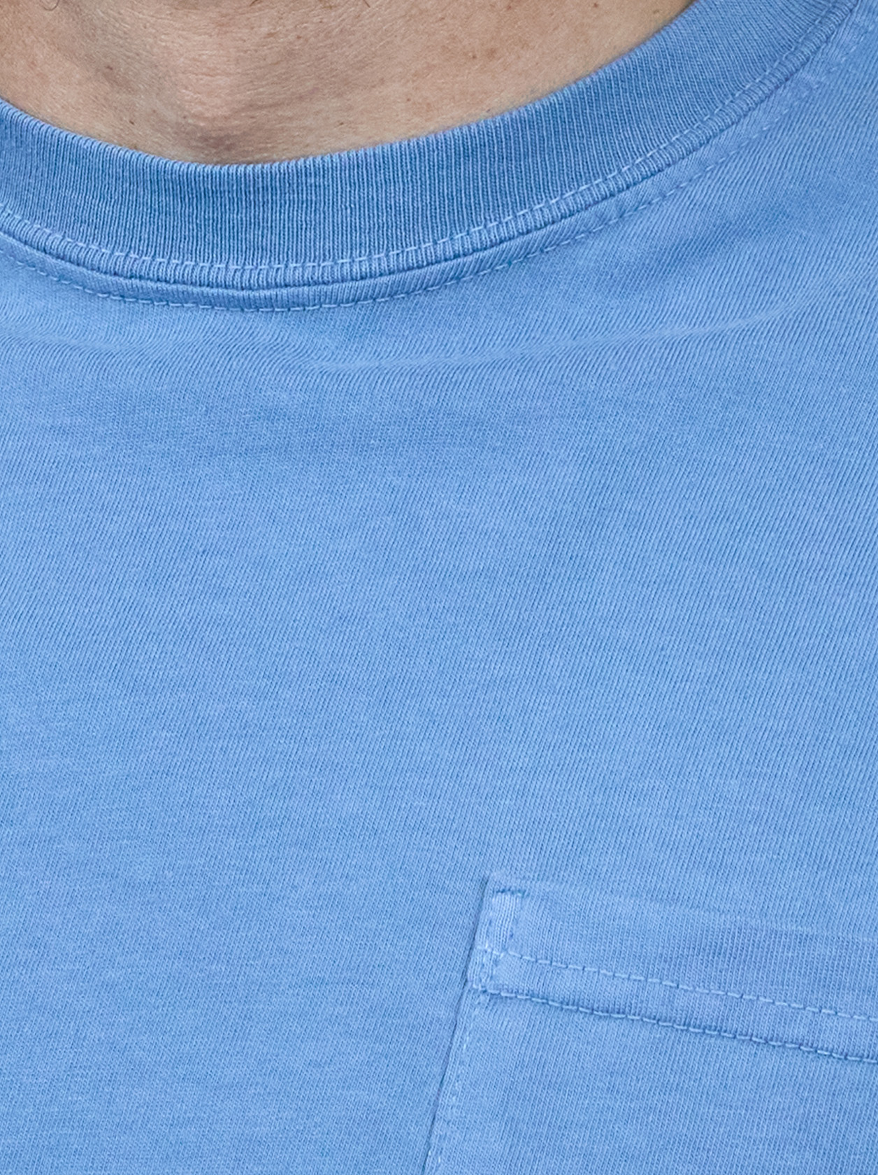 Close-up of a person wearing a blue T-shirt with a visible pocket and ribbed neckline.