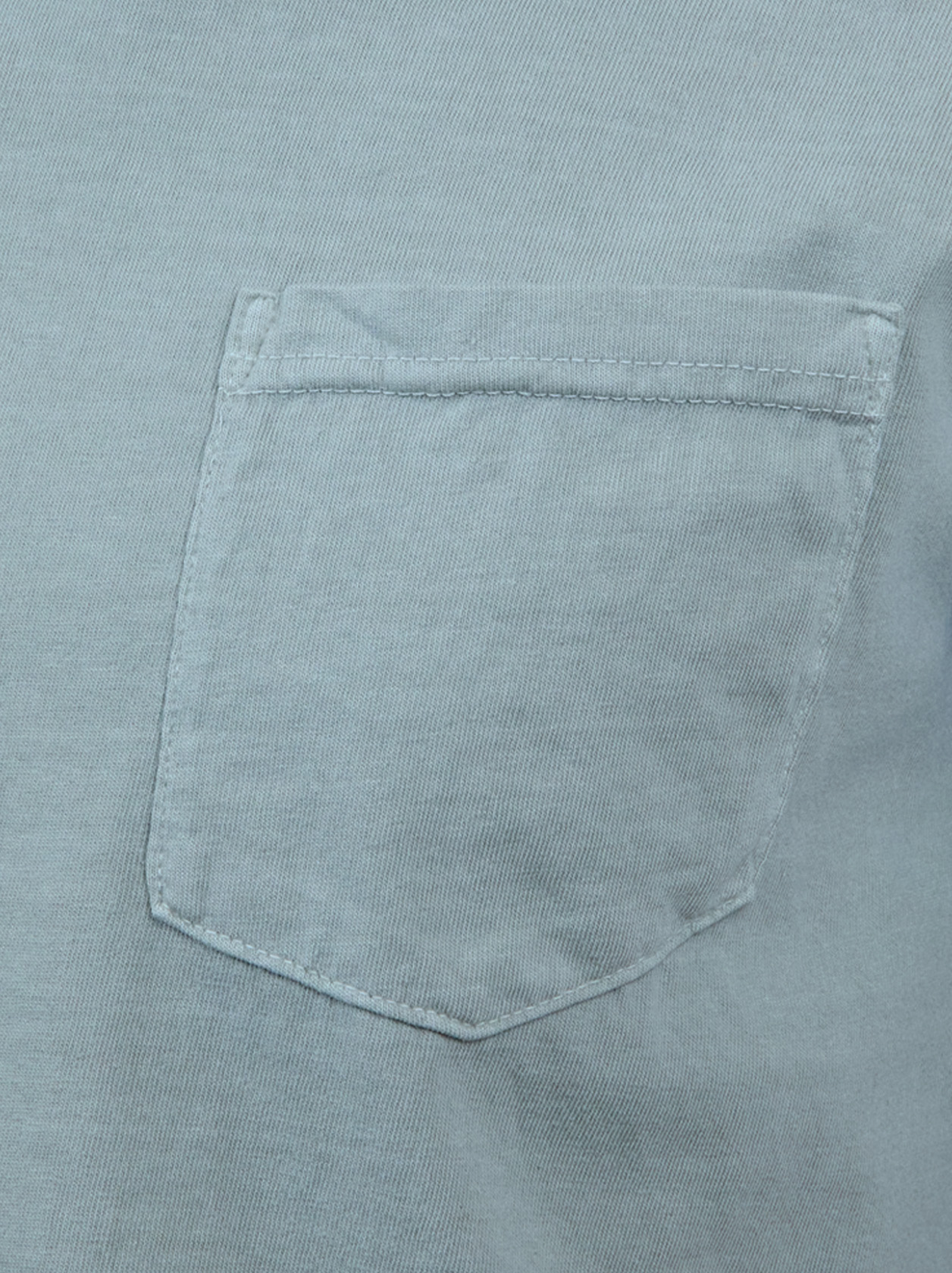 Close-up of a light blue fabric with a single chest pocket, showing detailed stitching and texture.