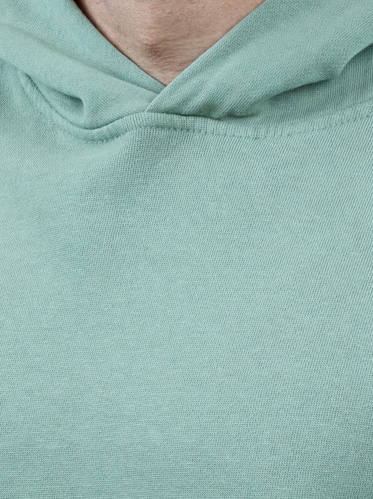 Close-up of a person wearing a light green hoodie, focusing on the fabric texture and neckline.