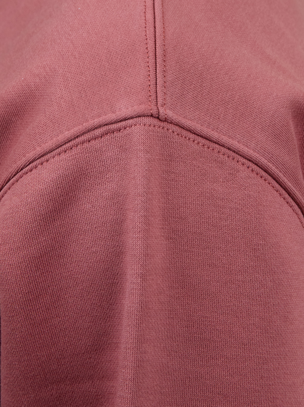 Close-up of a pink fabric with visible seams, showcasing texture and stitching details in a symmetrical pattern.
