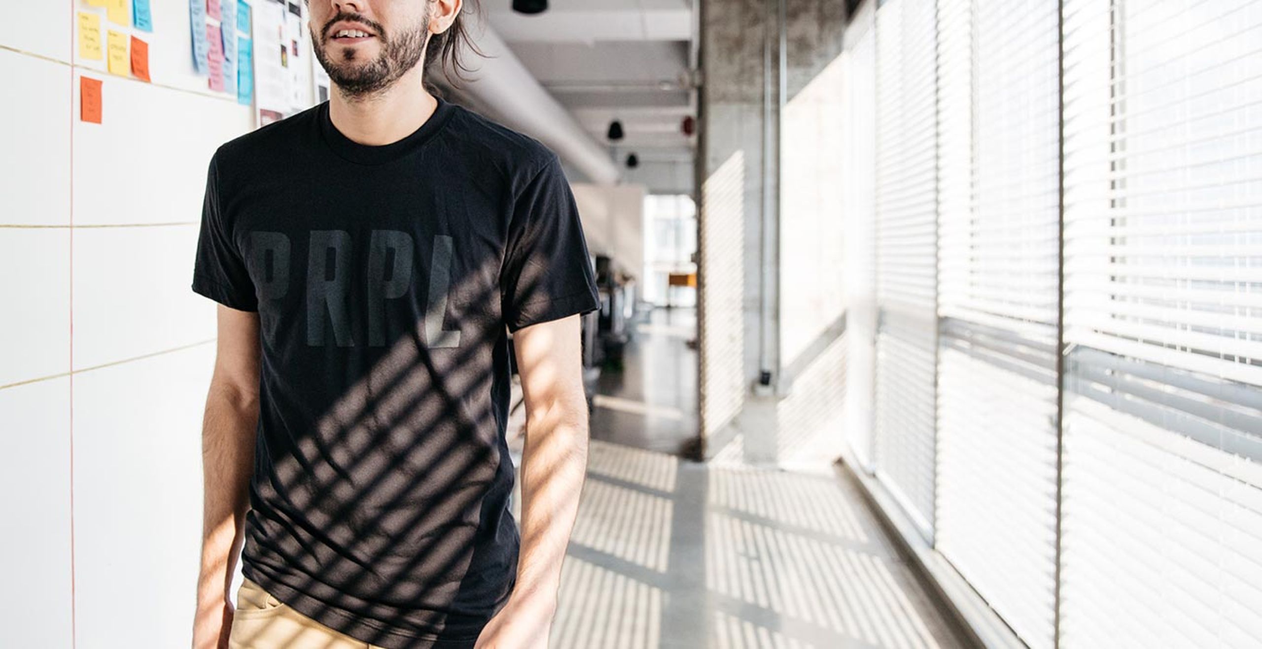 A man walks down the hallway wearing a shirt that says "PRPL" 
