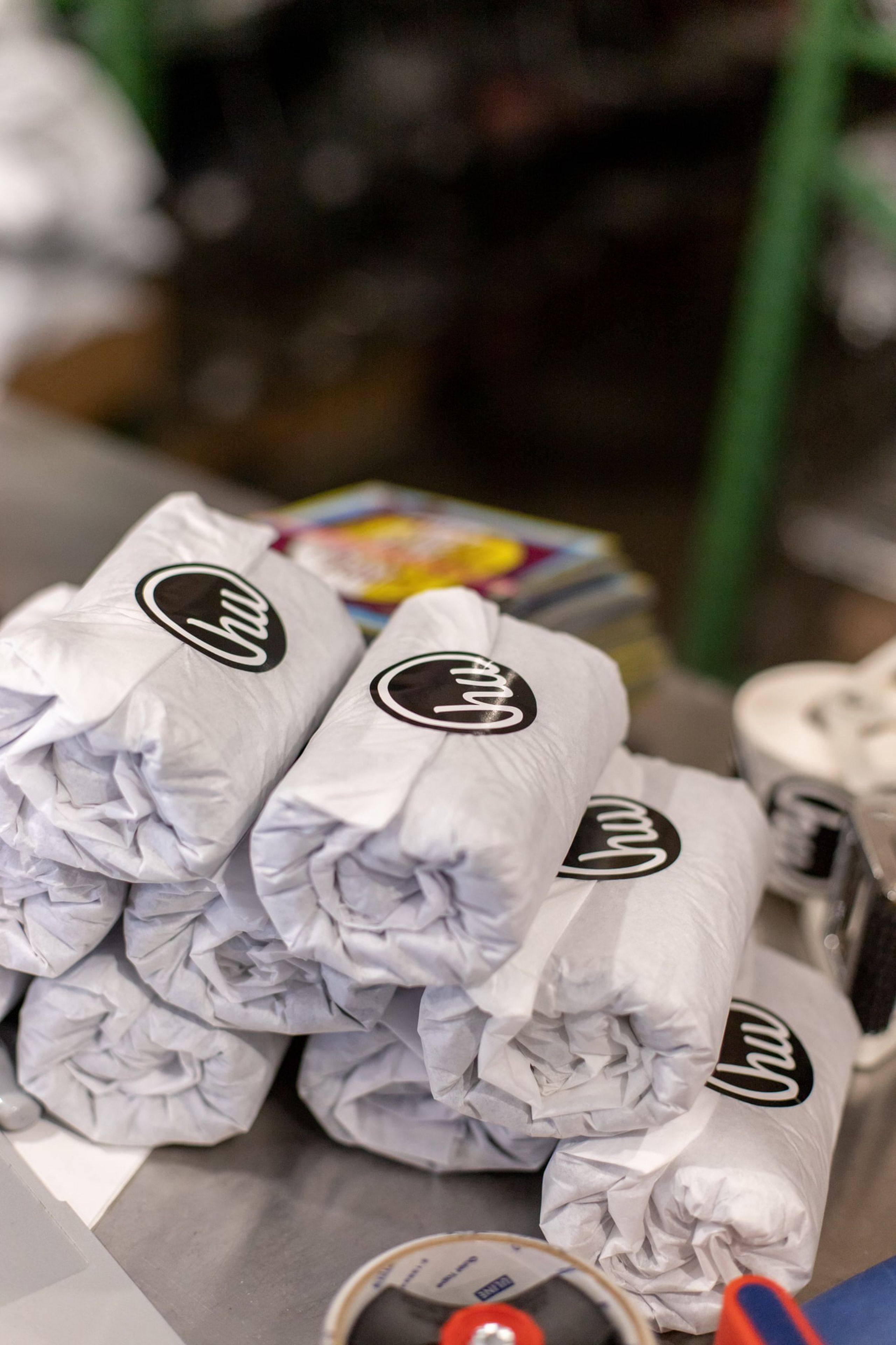 A stack of shirts rolled up in custom tissue paper