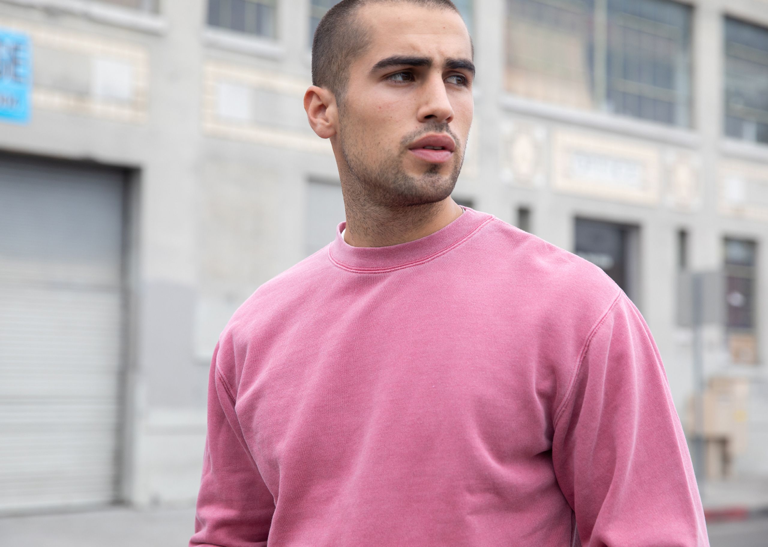 a man wearing a pink Independent PRM3500 crewneck sweatshirt