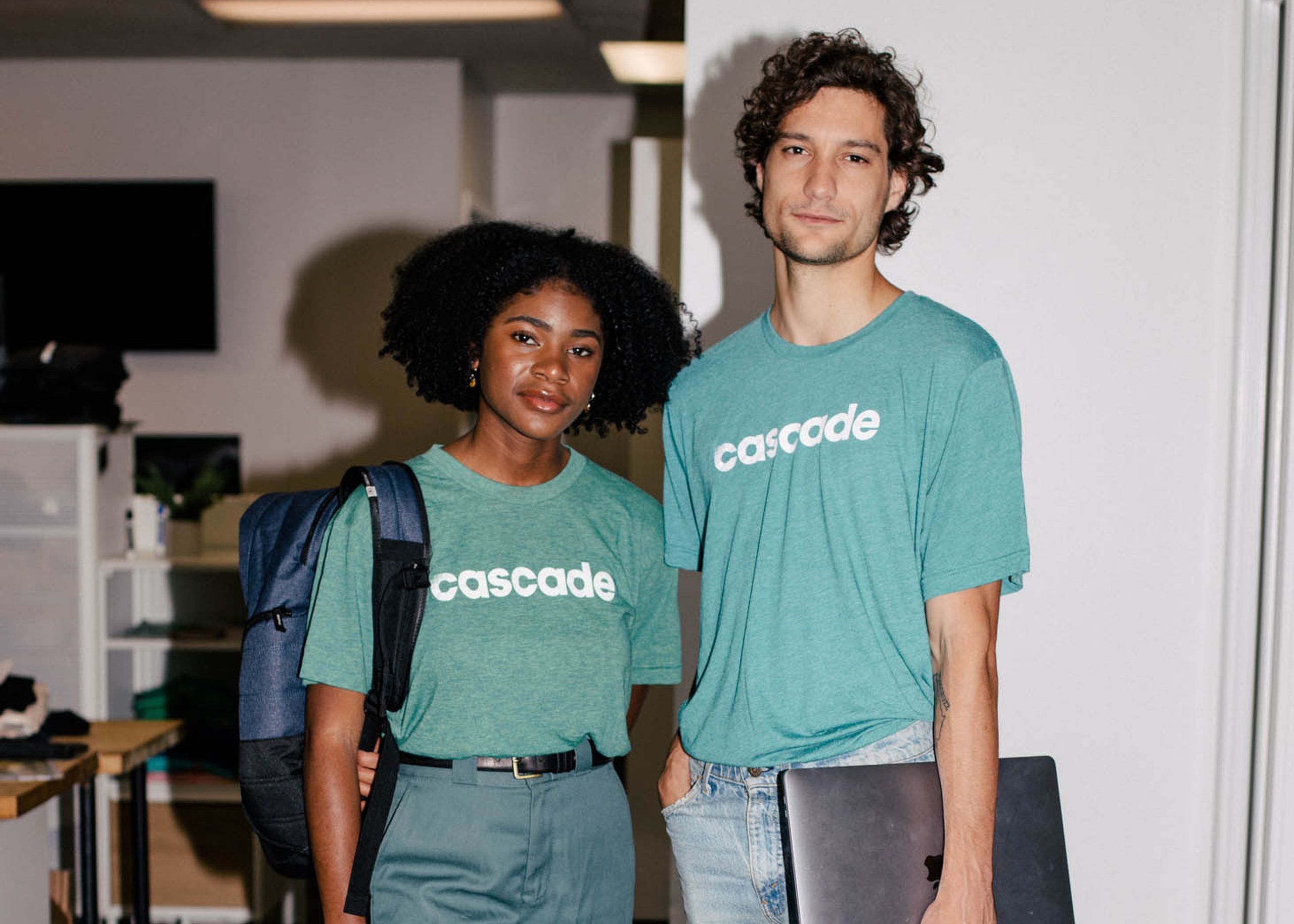 a women and man standing wearing teal t-shirts with the word cascade printed in white on them