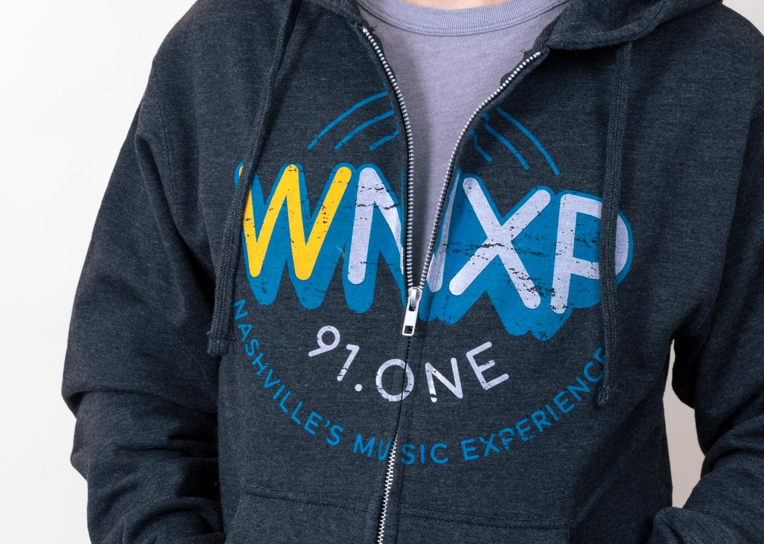 A man wears a radio station zip up hoodie with over the zipper printing