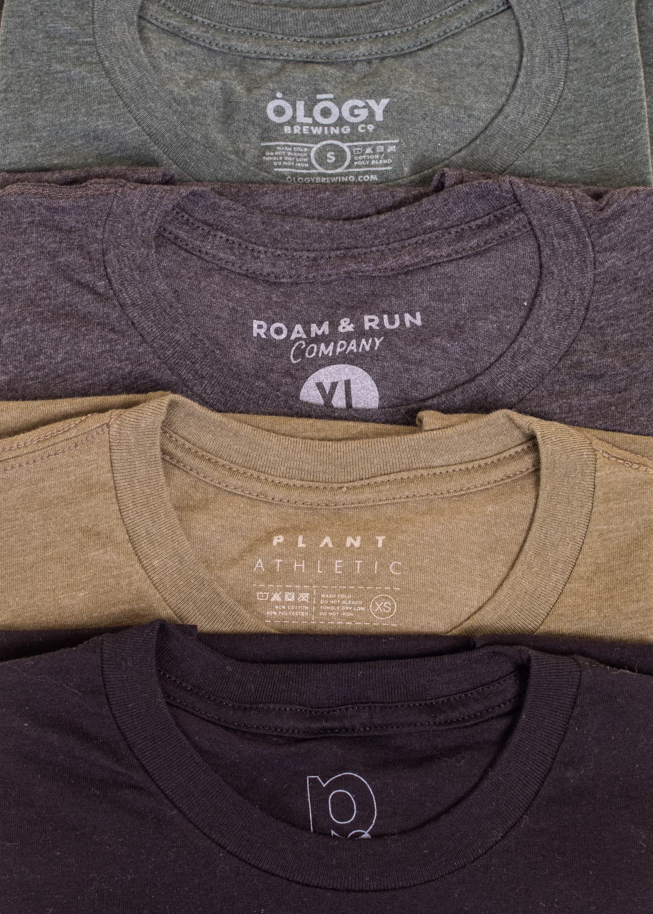 A stack of shirts in multiple colors, all with a heathered look and with custom printed tags 