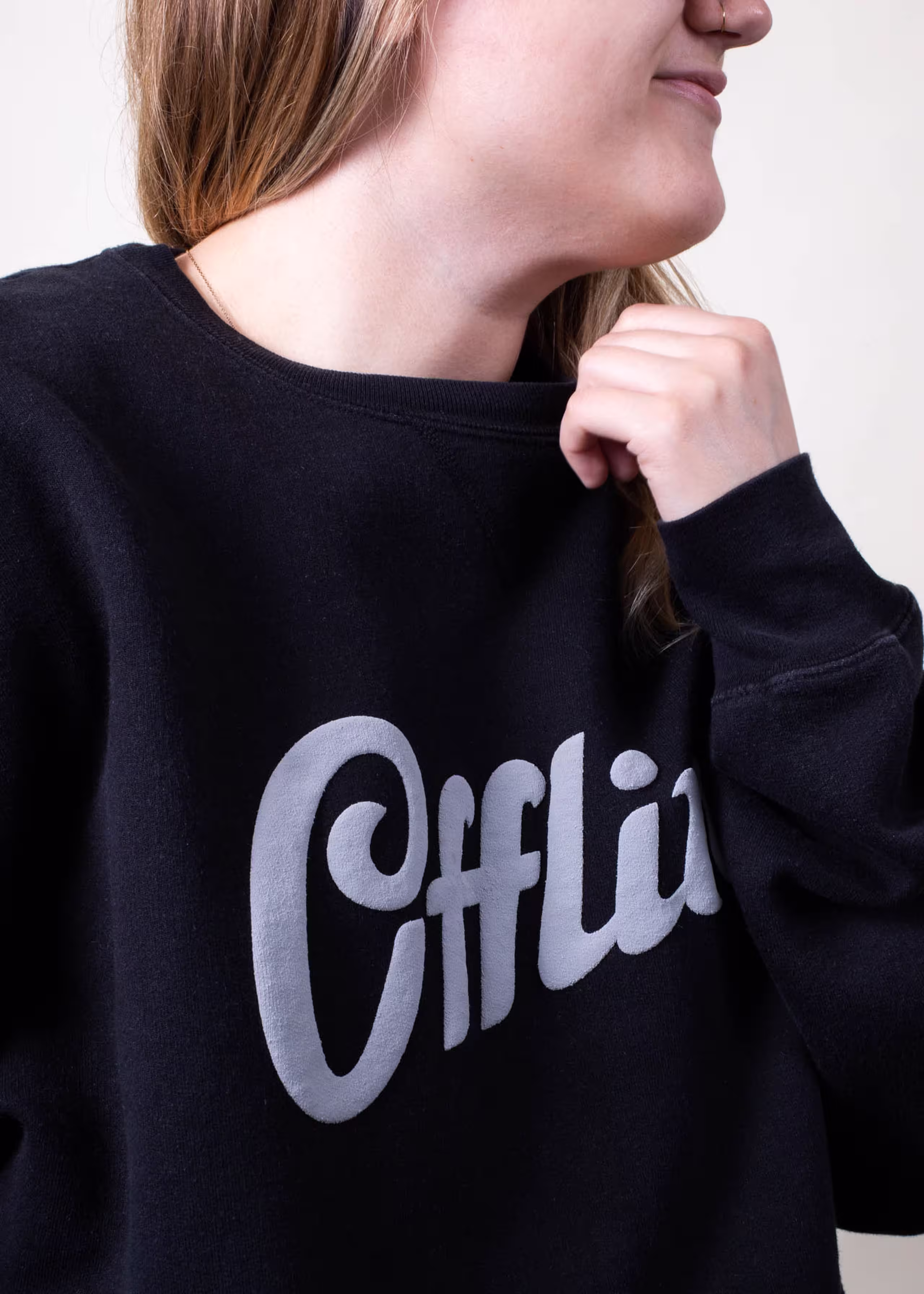 A girl wears a black sweatshirt with a white puff ink design printed on it 