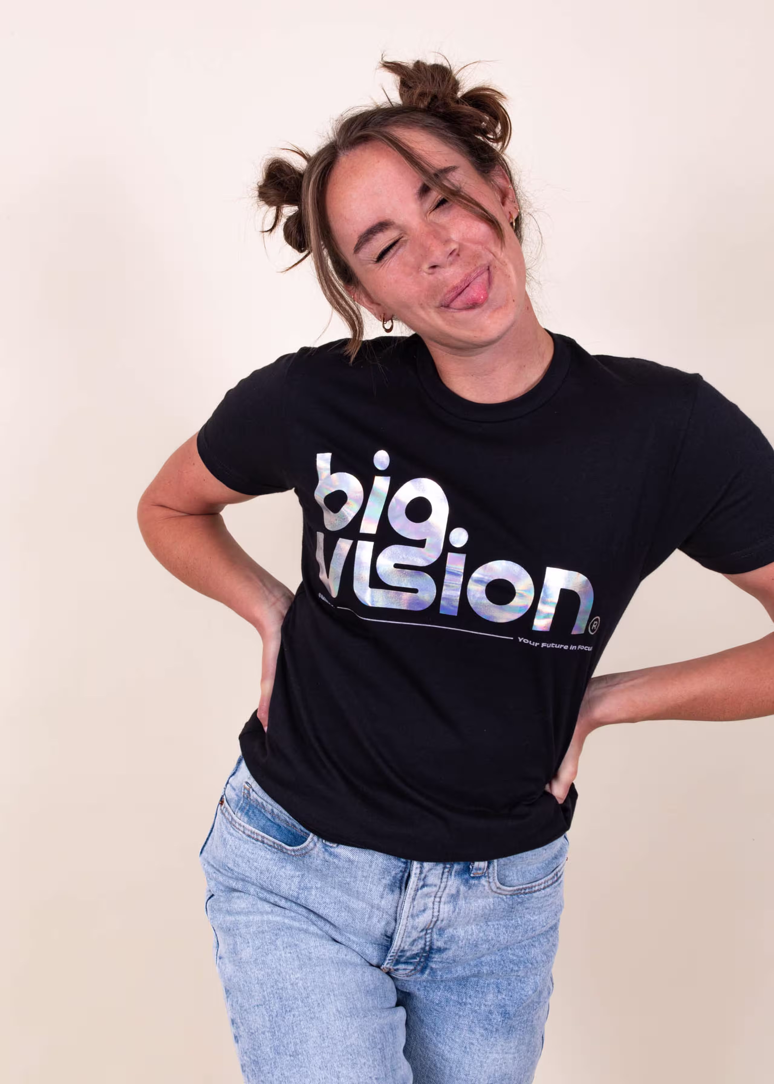 A girl sticks her tongue out playfully while wearing a shirt that says "big vision" printed with metallic foil 