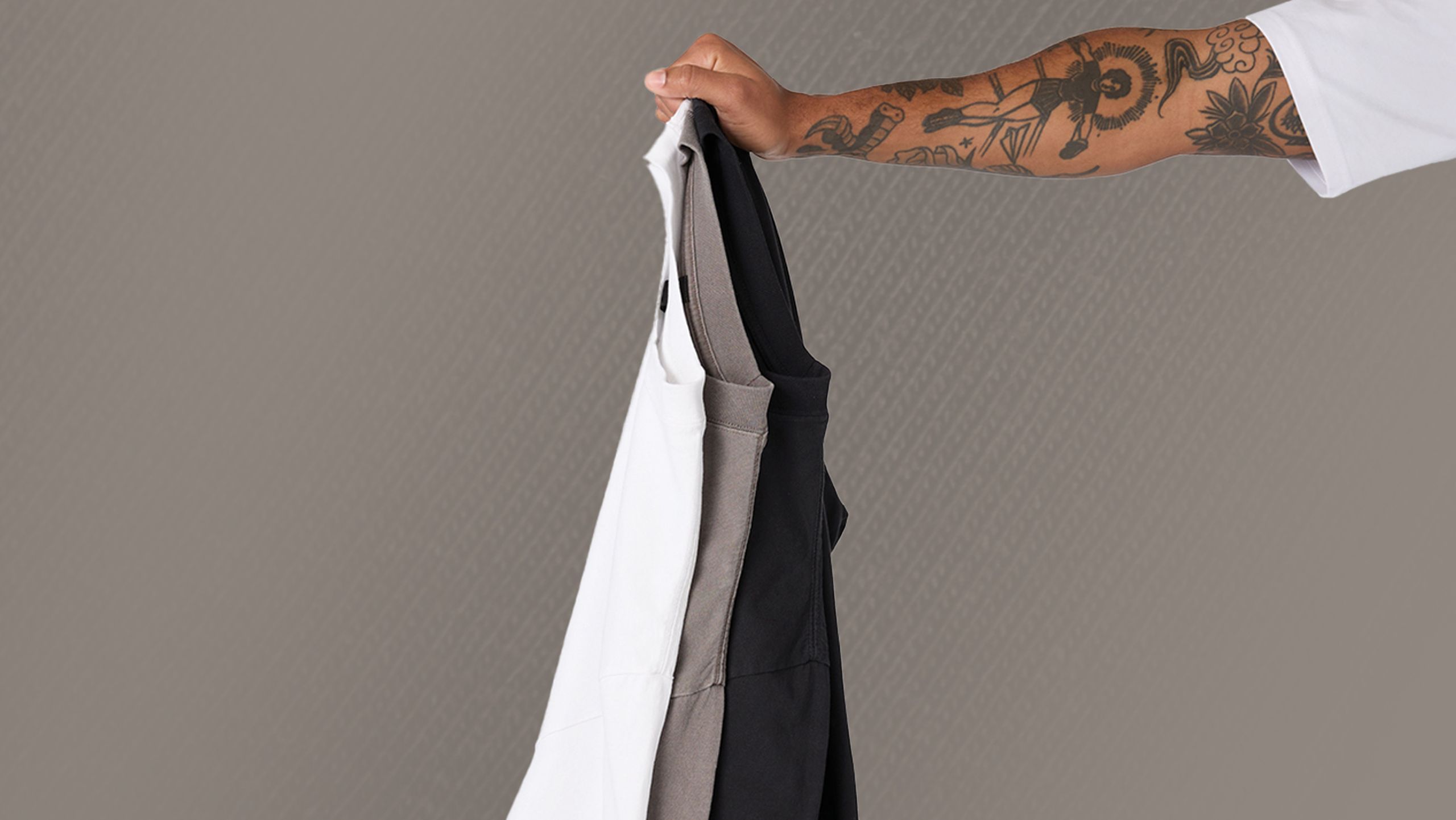 someone holding three t-shirts