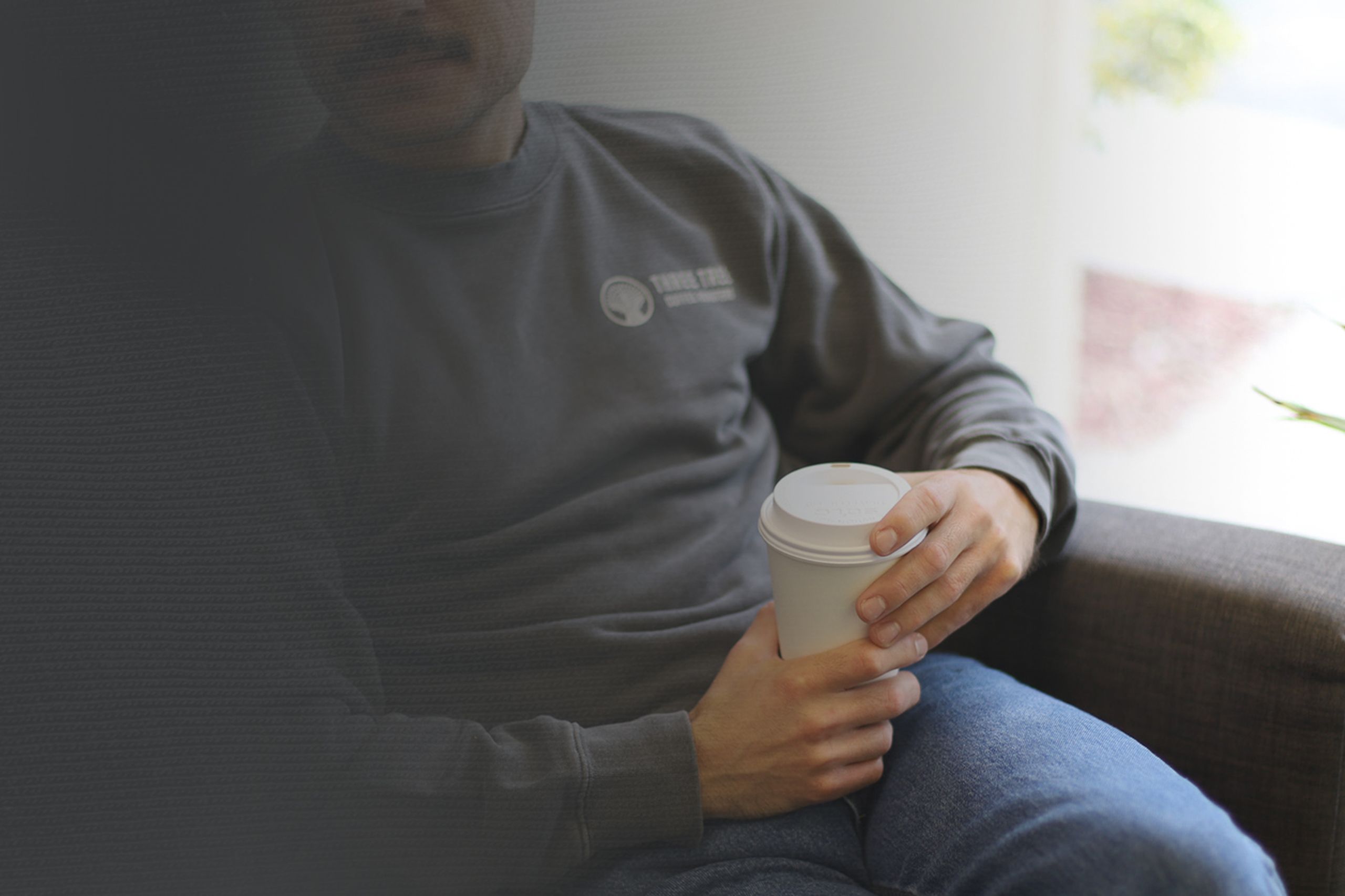 man wearing a grey crewneck sweatshirt with a coffee