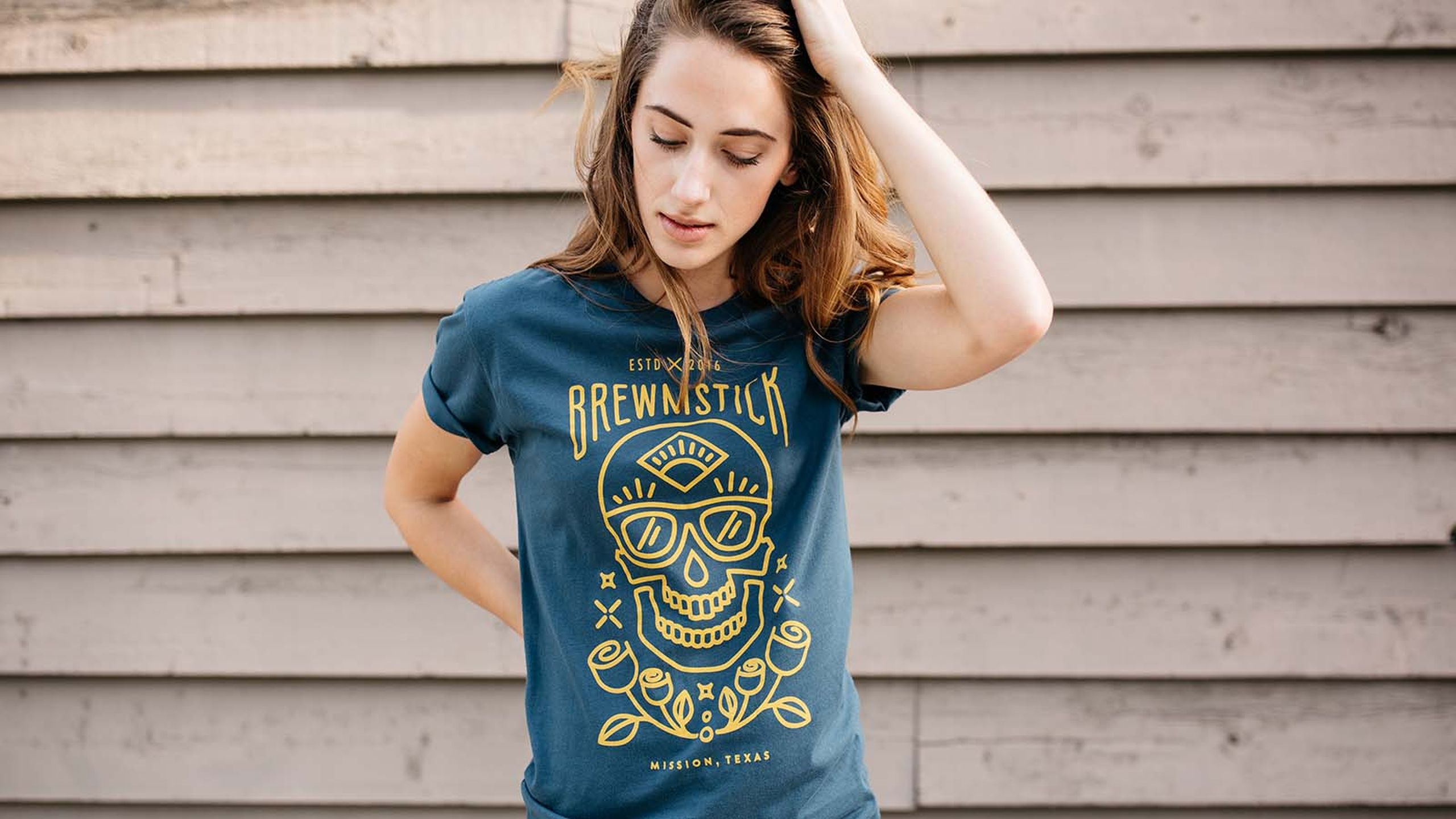 women wearing a green-blue shirt with a yellow outline of skull and roses