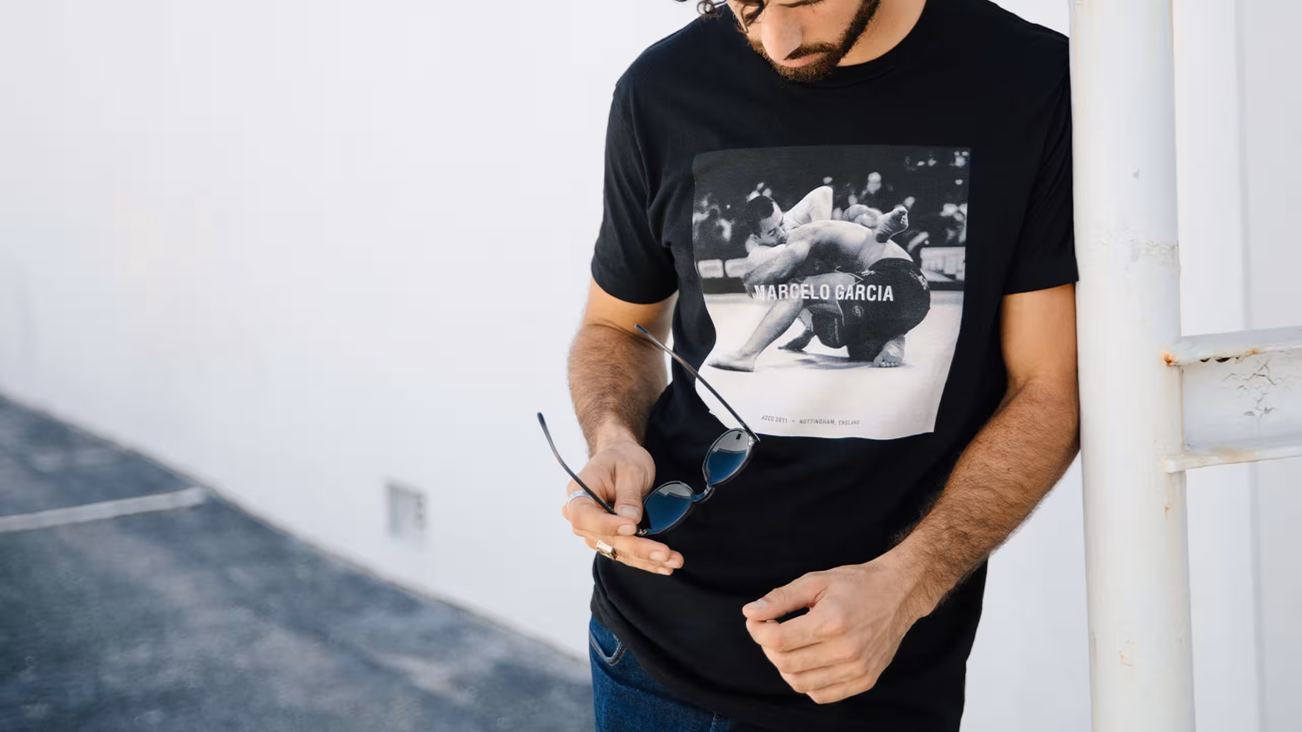 man wearing a black t-shirt - holding sunglasses