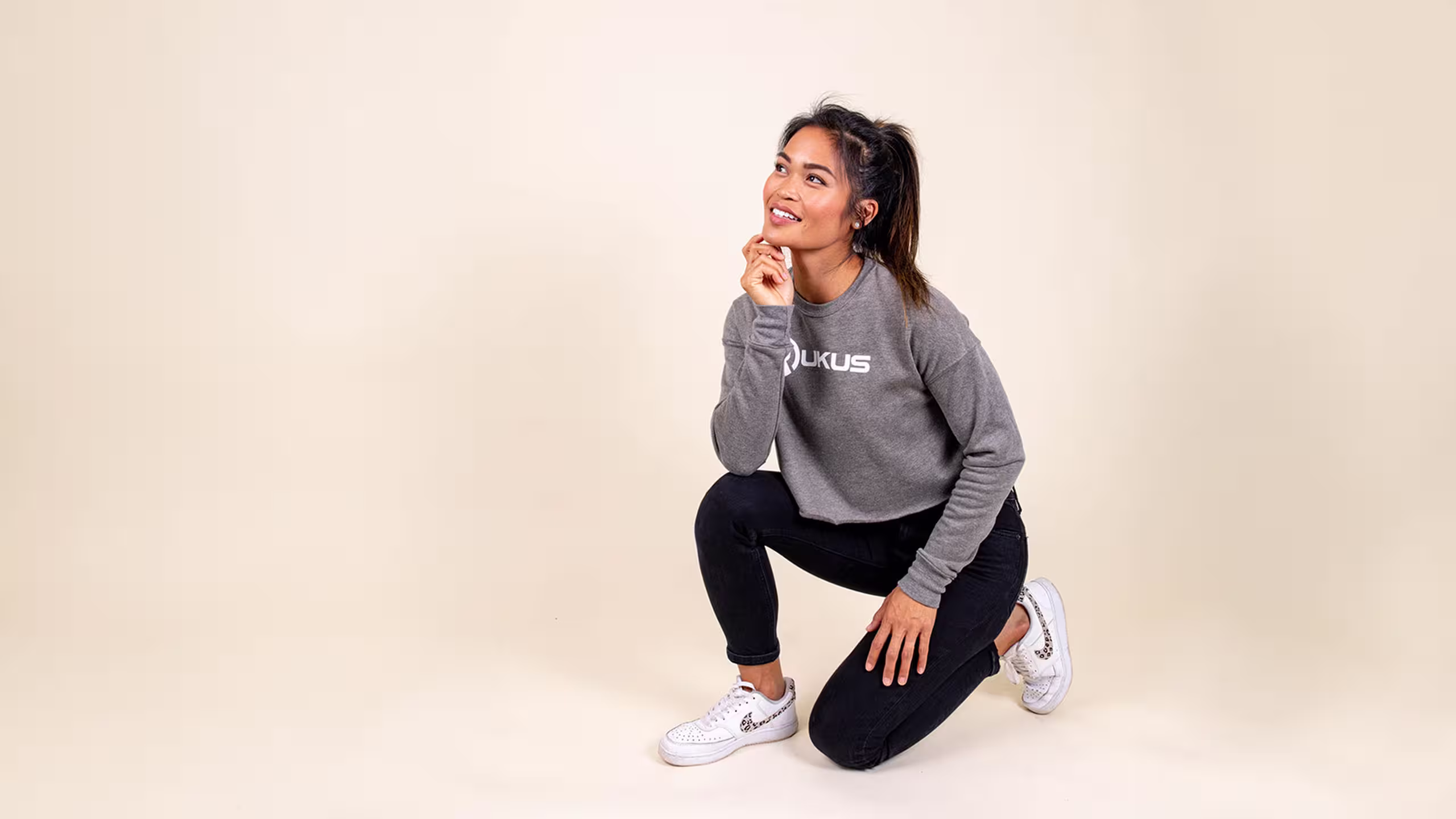women kneeling with a grey cropped sweatshirt on