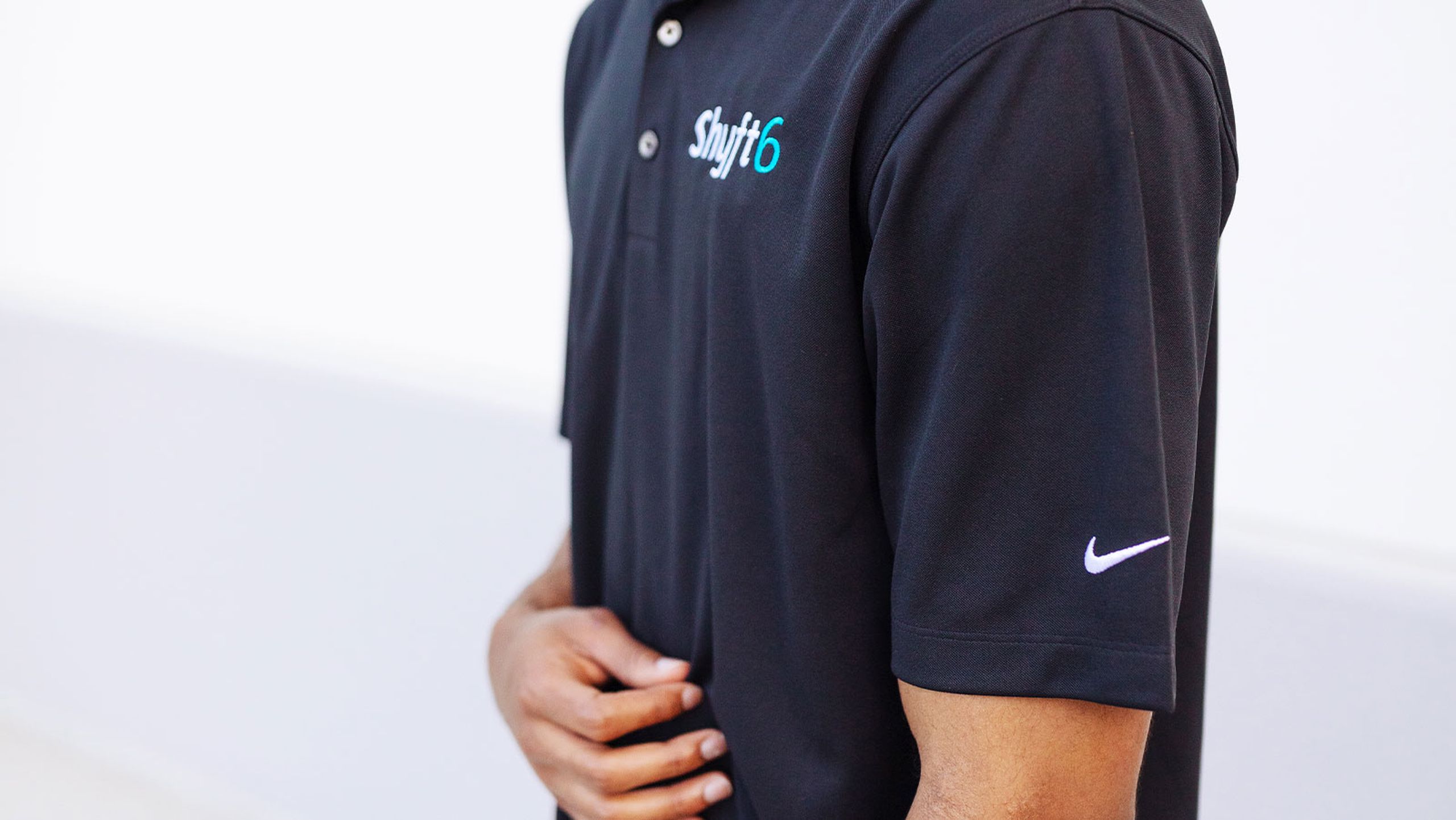 Man wearing a navy Nike polo that has an embroidered company logo