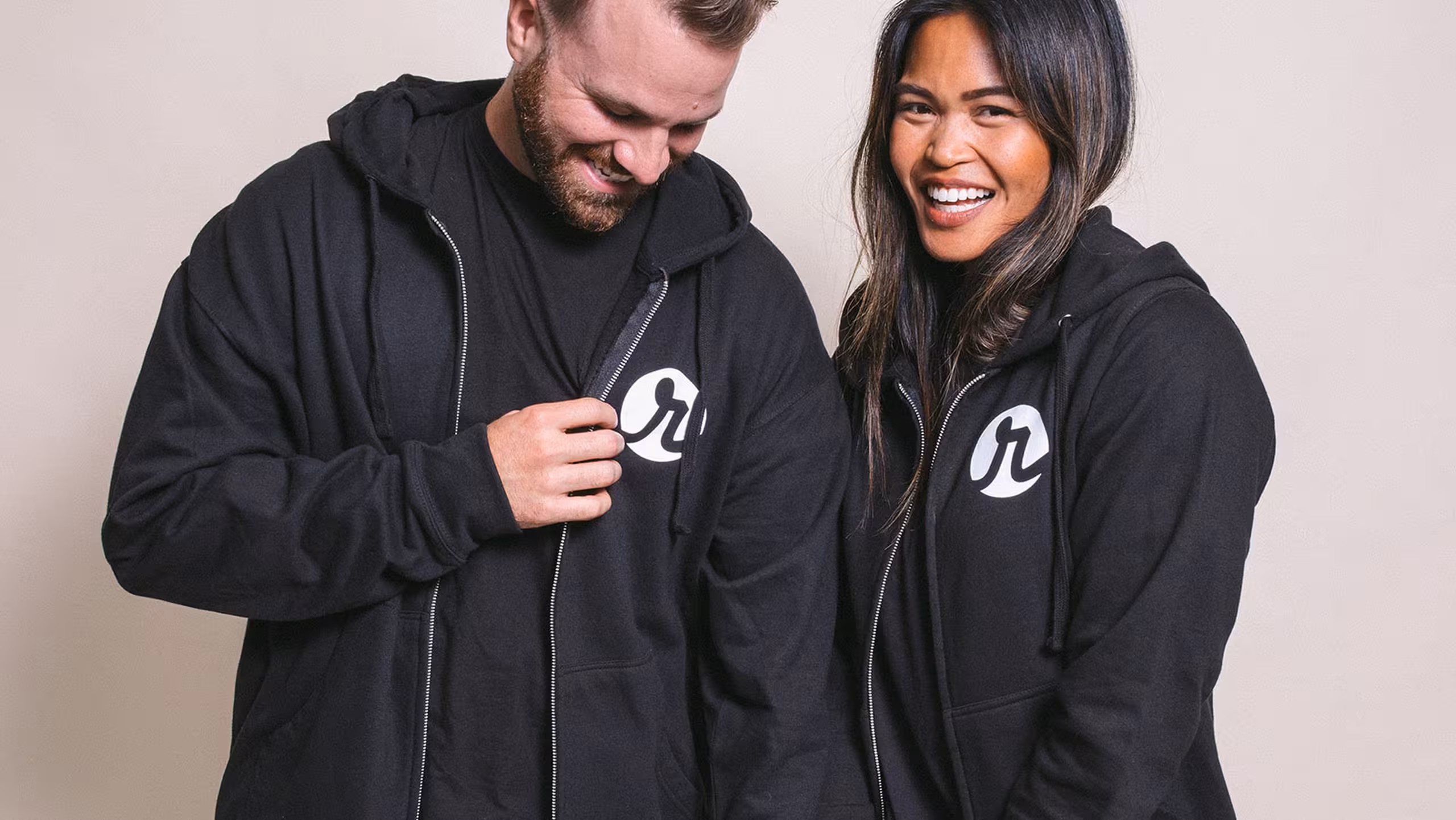 two people wearing black zip-up hoodies