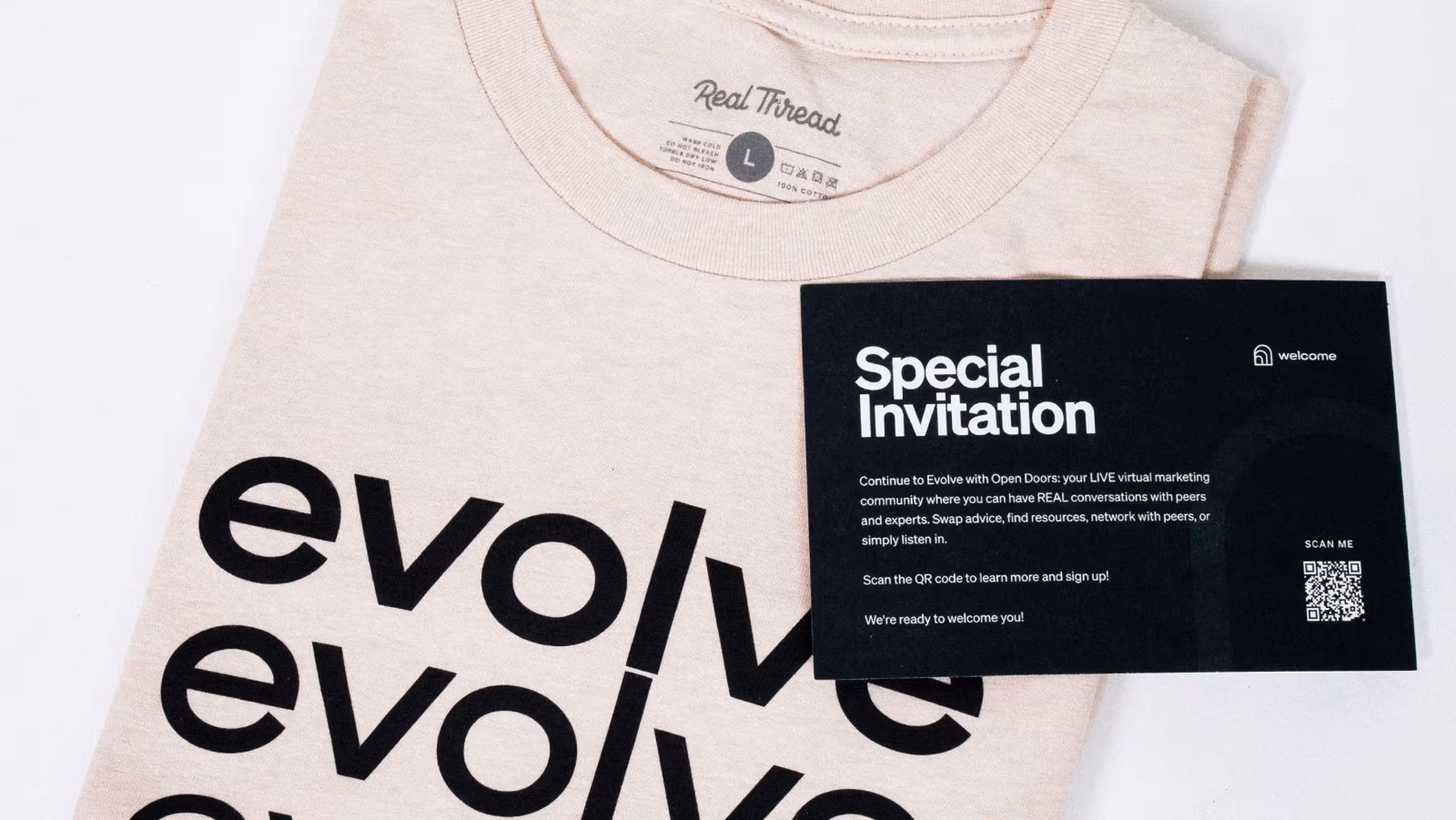 white folded shirt with evolve printed in black. laying on top is a black card