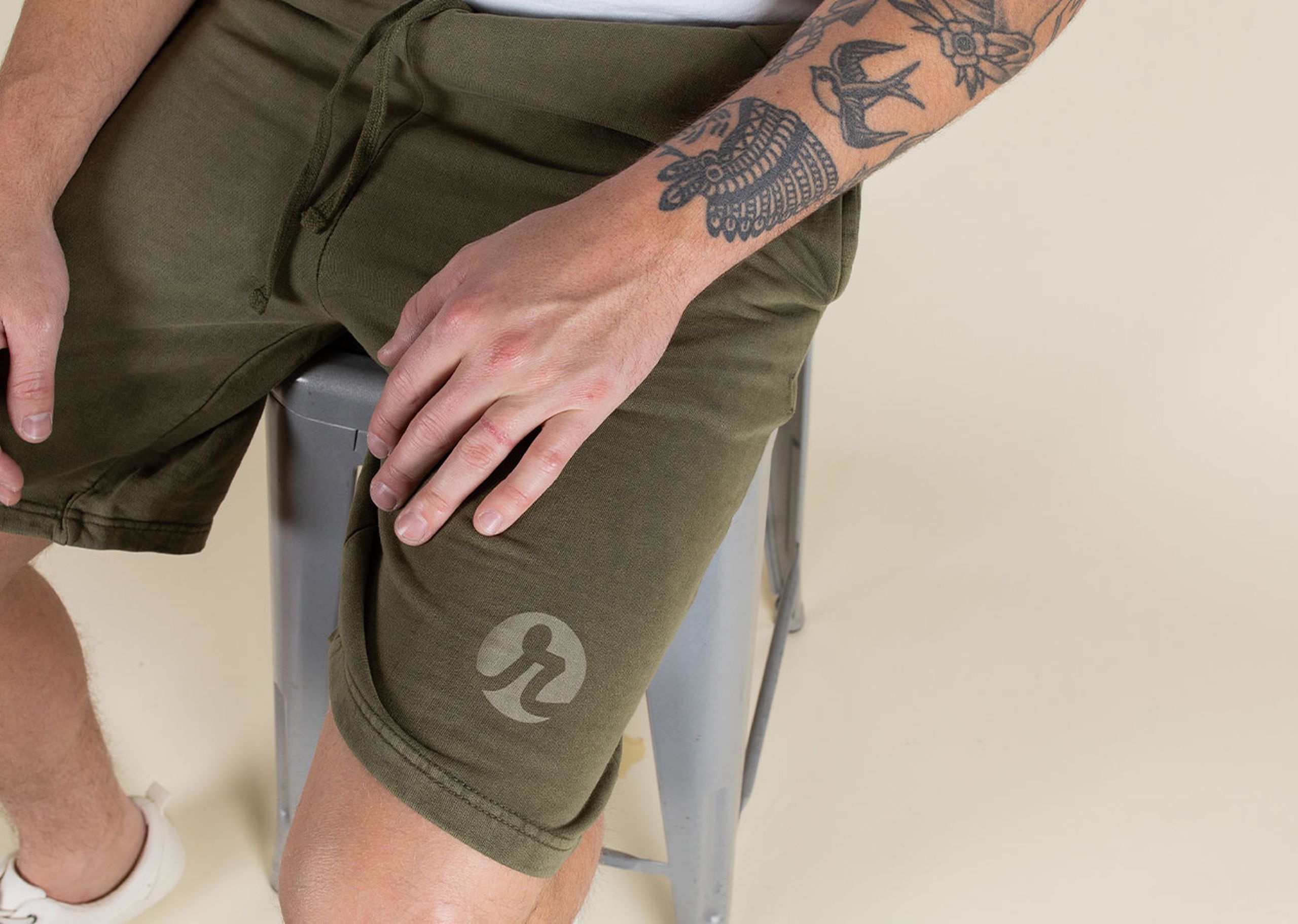 man sitting on a stool with olive shorts
