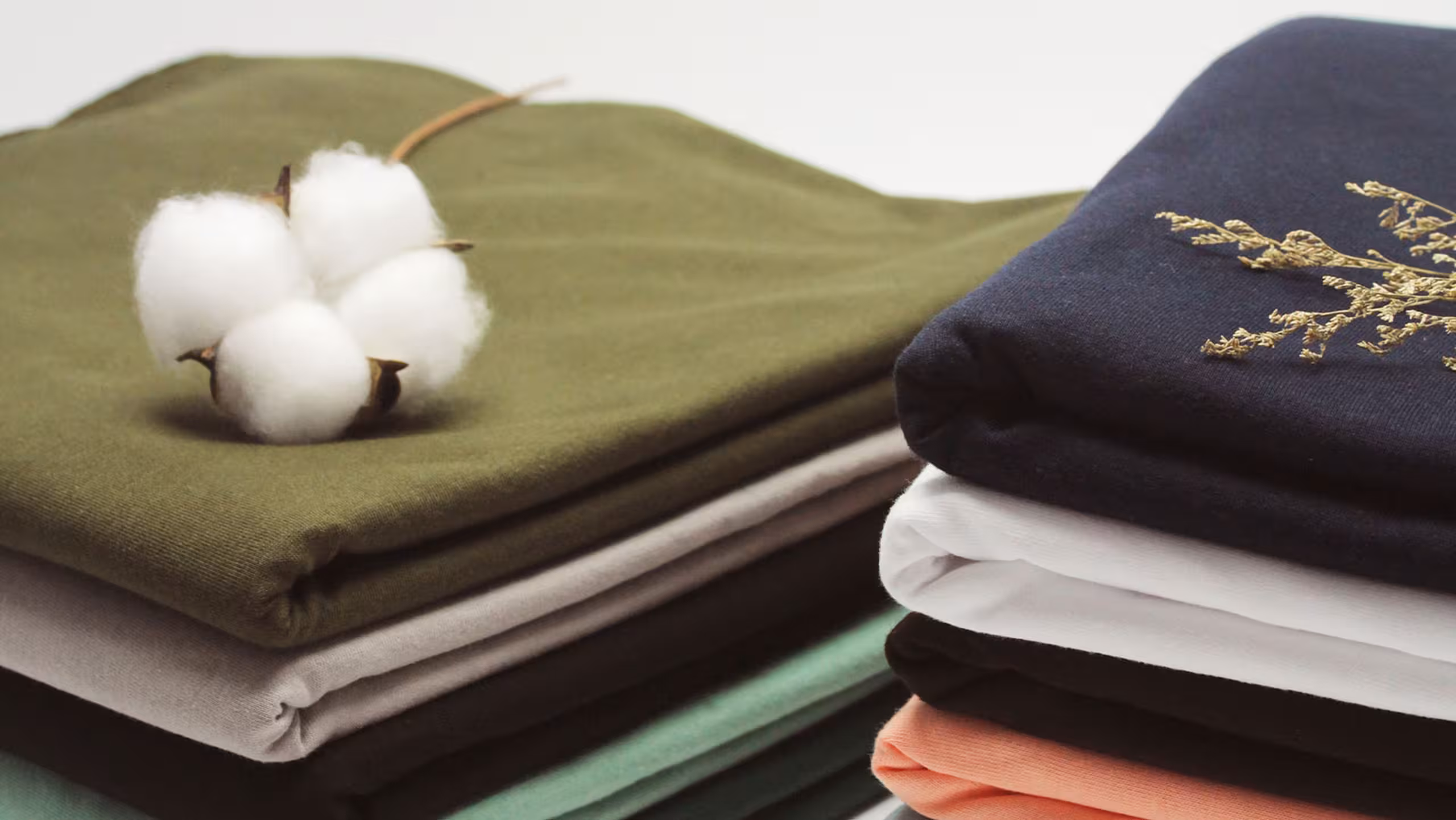stack of t-shirts folded with cotton sitting on top
