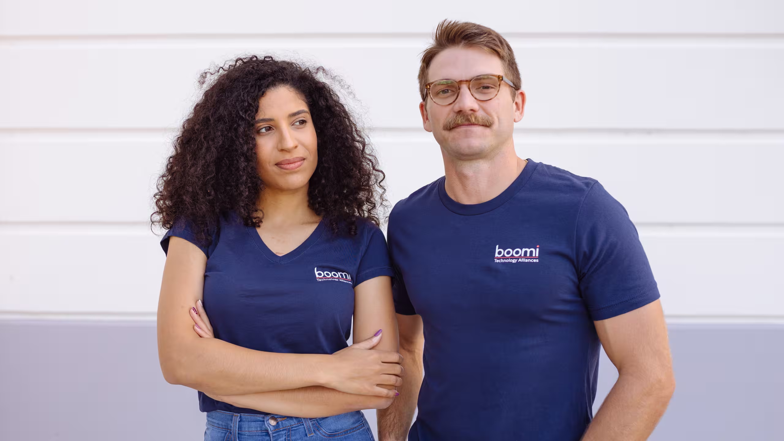a man and woman wearing a navy T-shirt with a logo on the top-left of the t-shirt