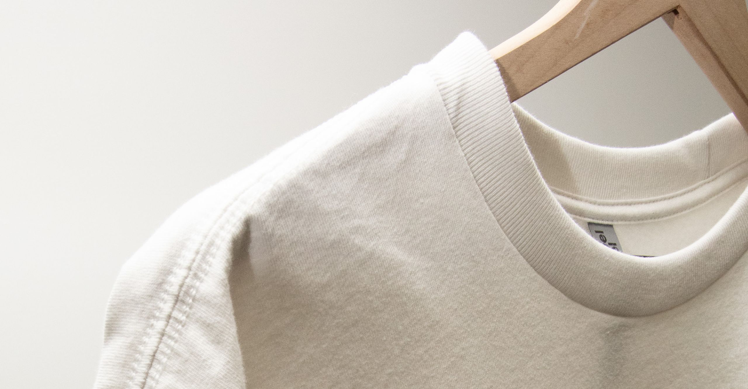 close-up to a white next level heavyweight hanging on a wood hanger