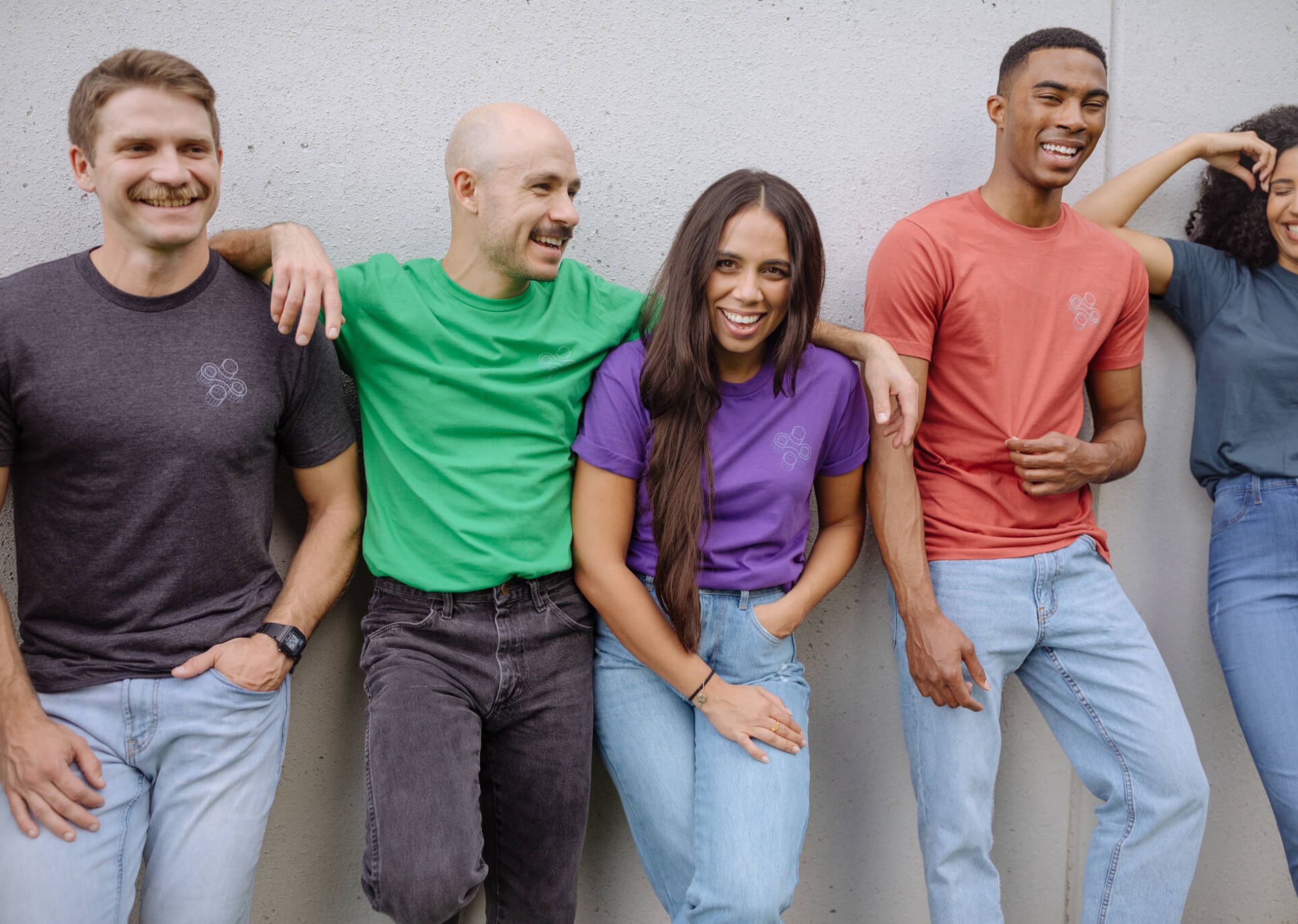 A group of people all wear a shirt printed with the same design, but on different colored garments 