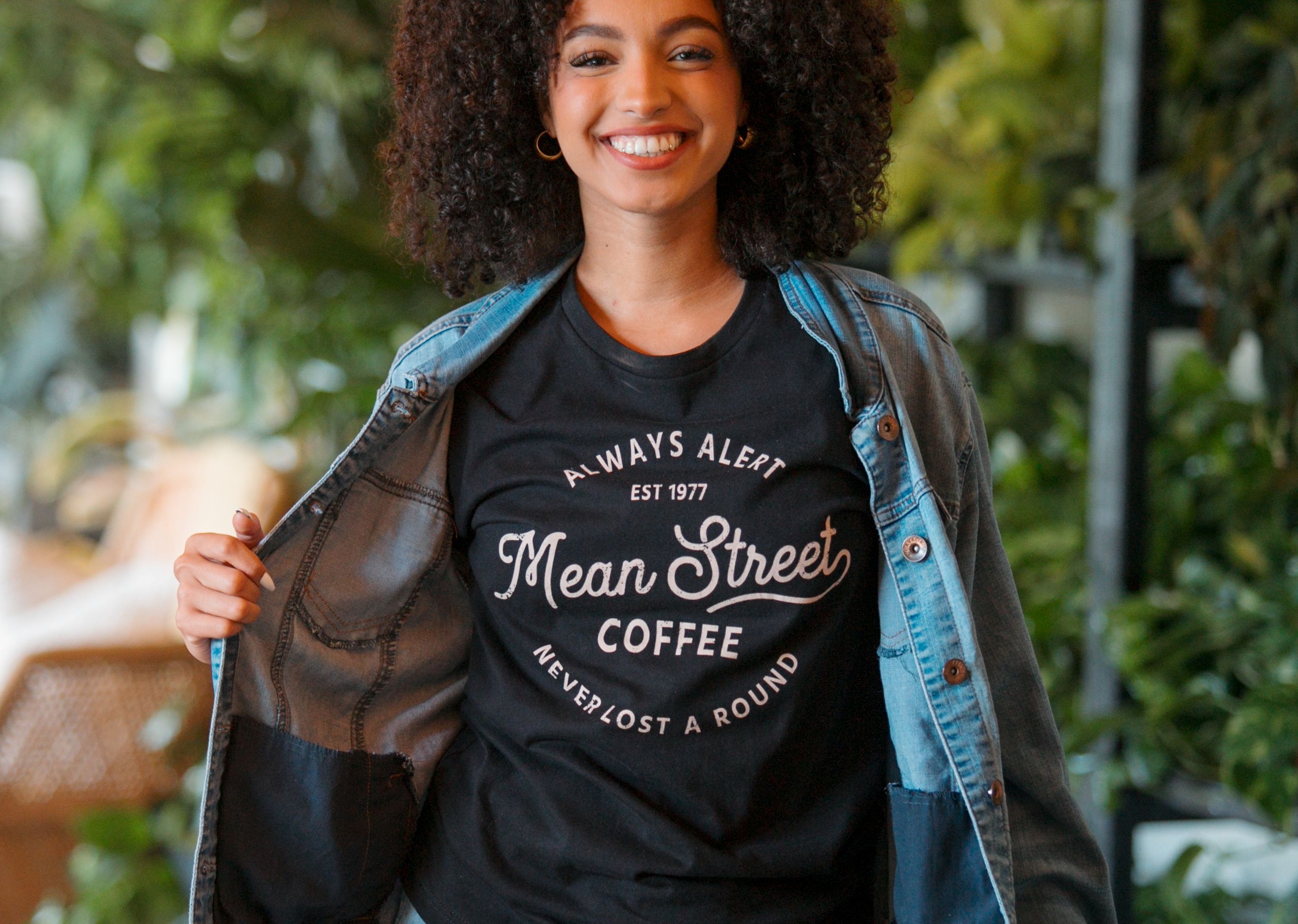woman smiling while wearing jean jacket and graphic t-shirt