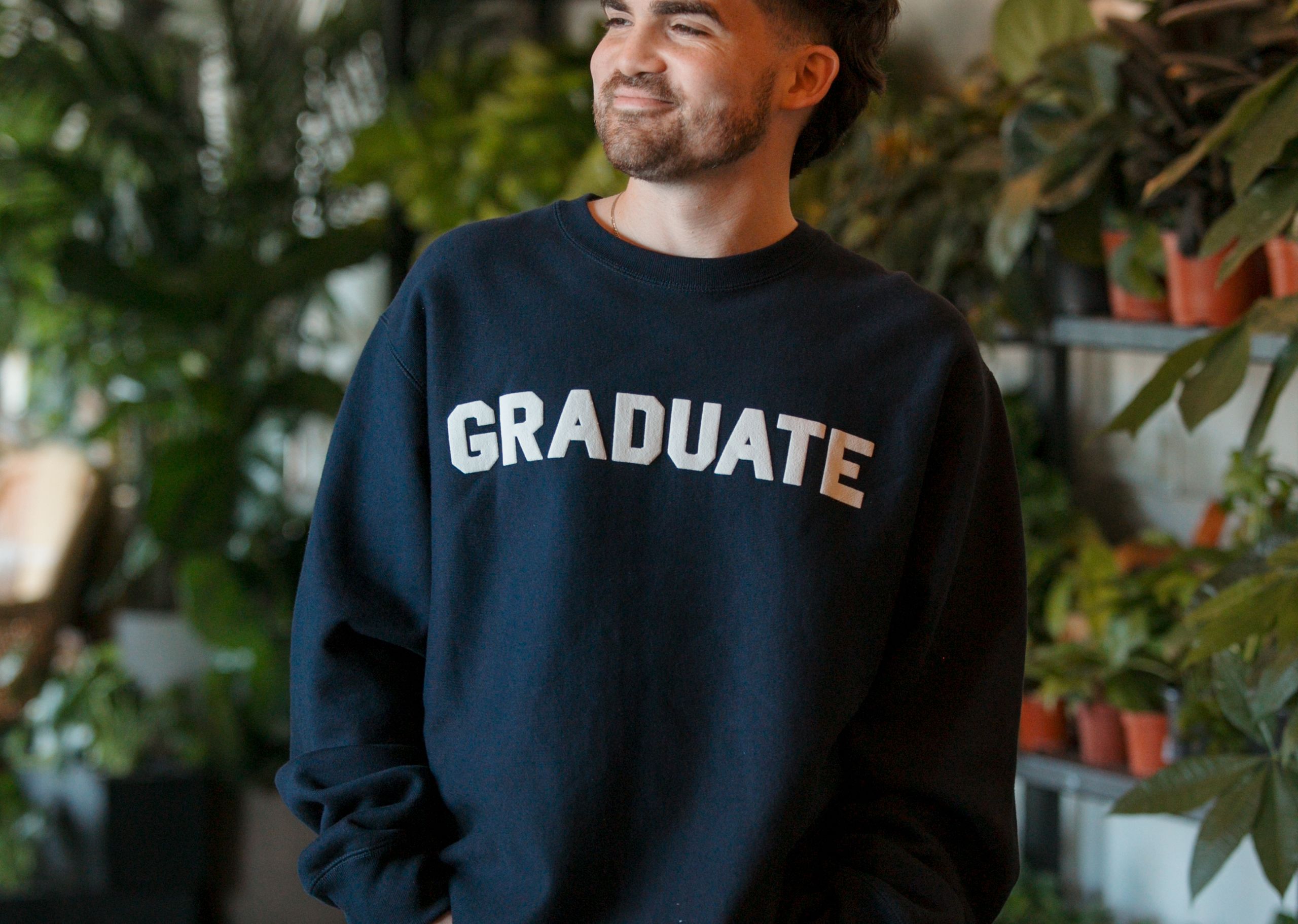 man wearing a dark navy hoodie with the word graduate printed in white puff print