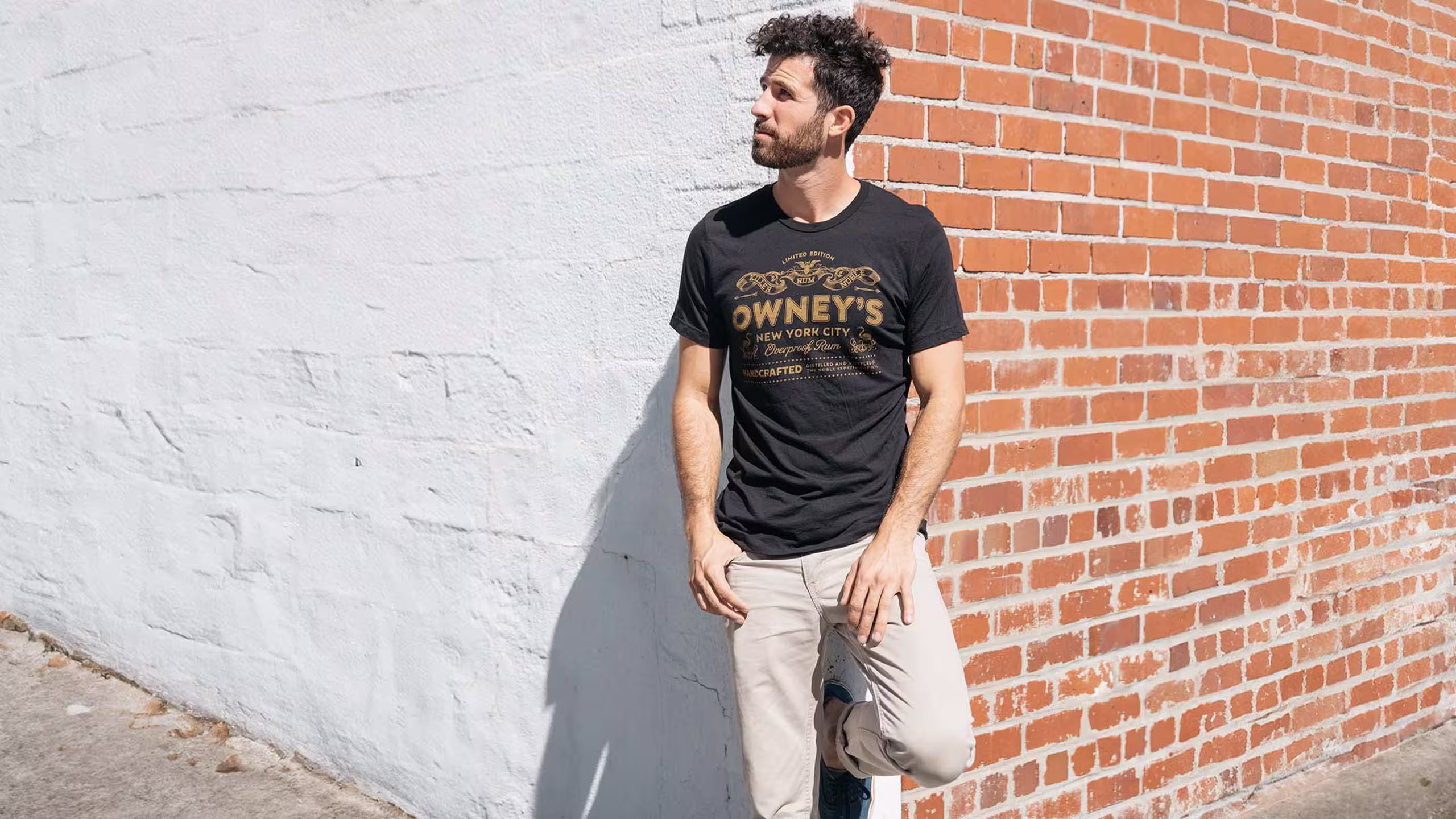 man leaning on a wall wearing a black t-shirt