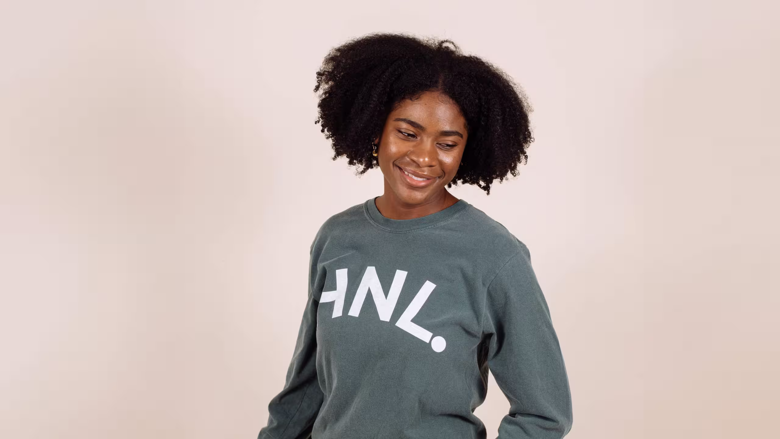 Women wearing a green crewneck sweatshirt with HNL. printed on it