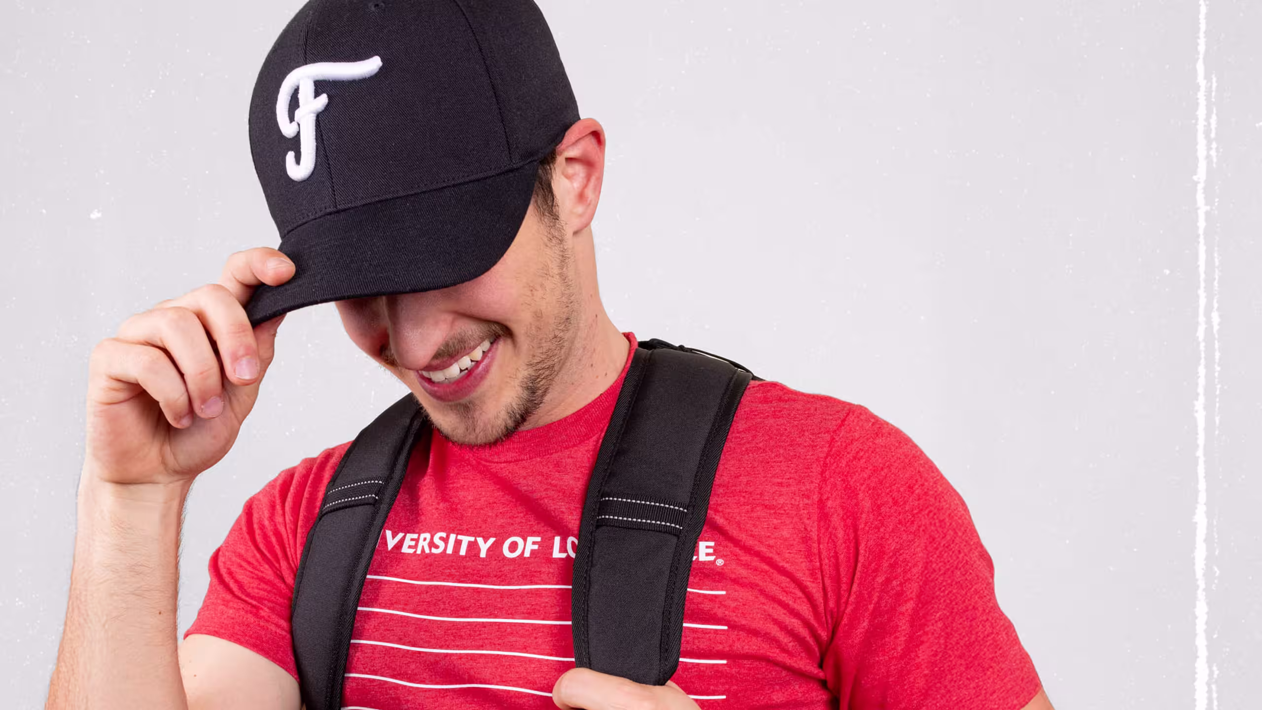 man in a red t-shirt with a black backpack and black hat