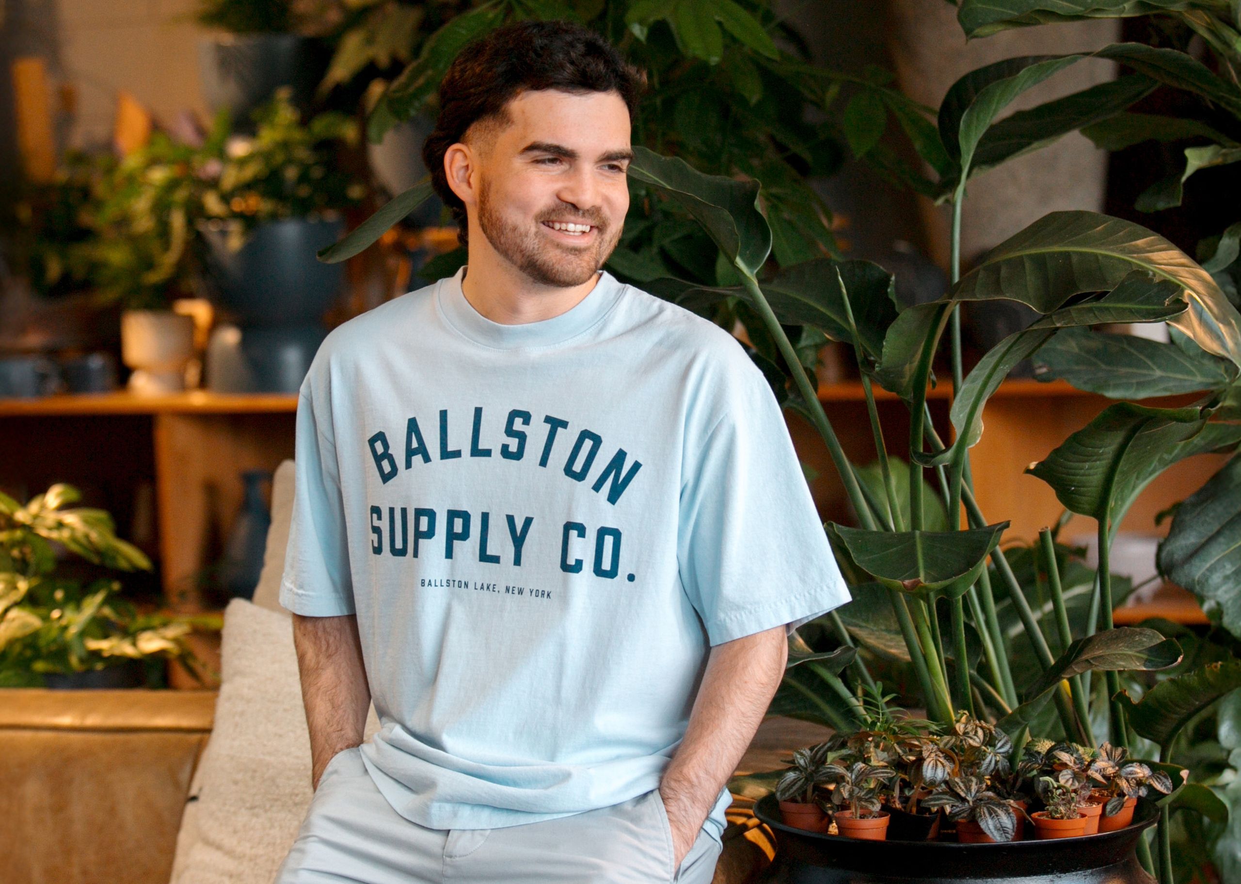 man wearing a light blue tee with the words ballston supply co printed on it