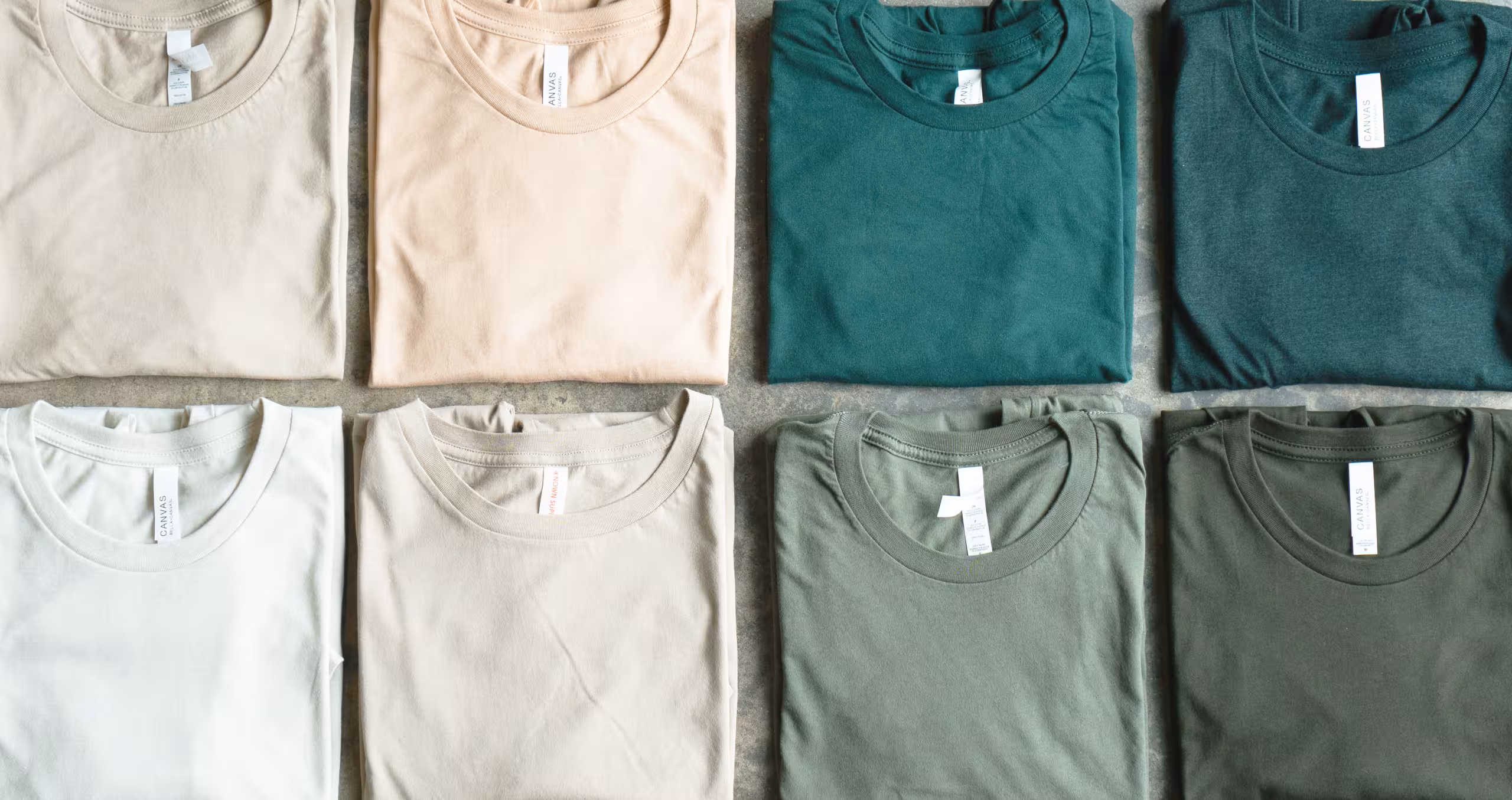 an arrangement of neutral and green shirts, folded, in a grid