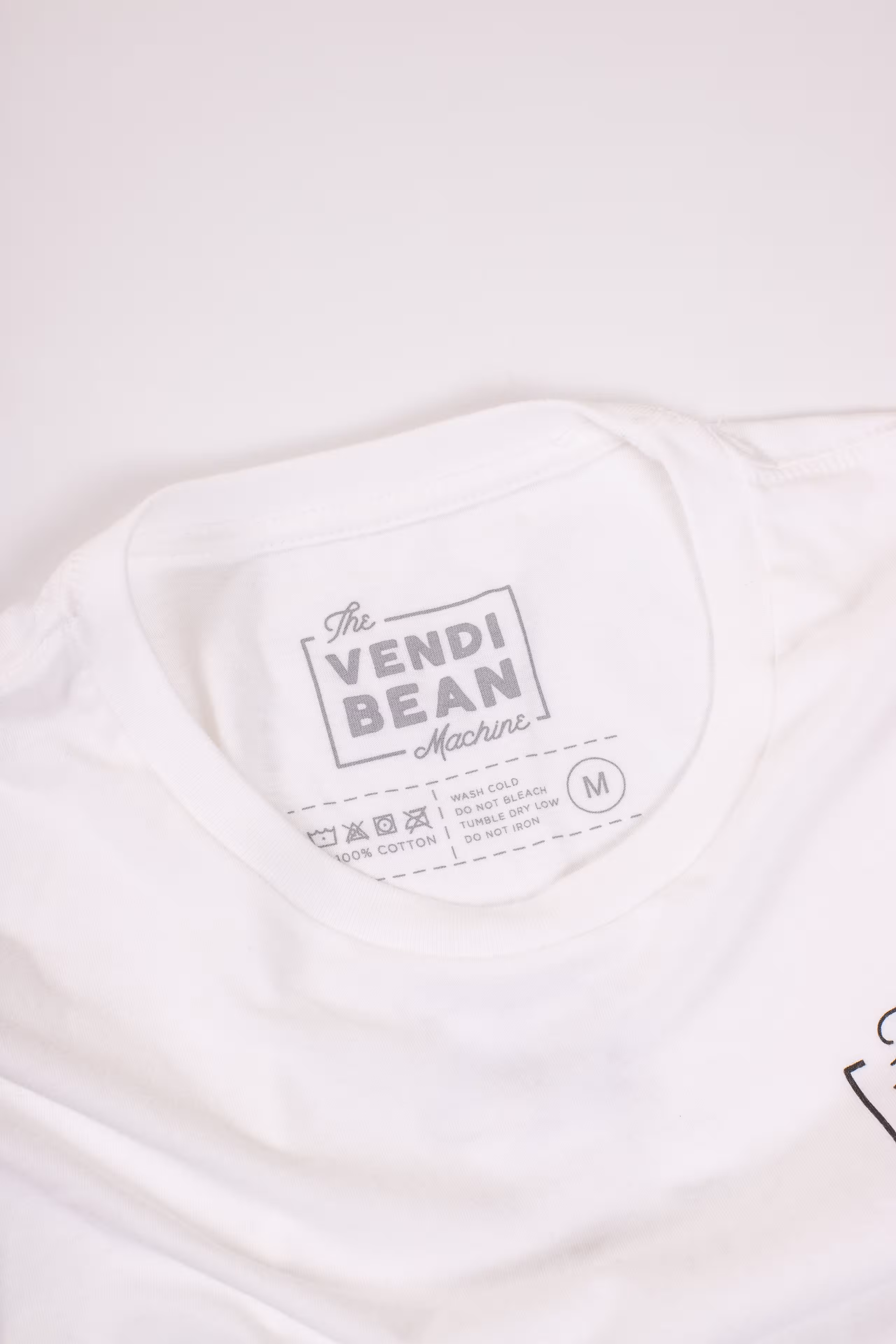 A custom printed tag for the Vendi Bean Machine on a white shirt 