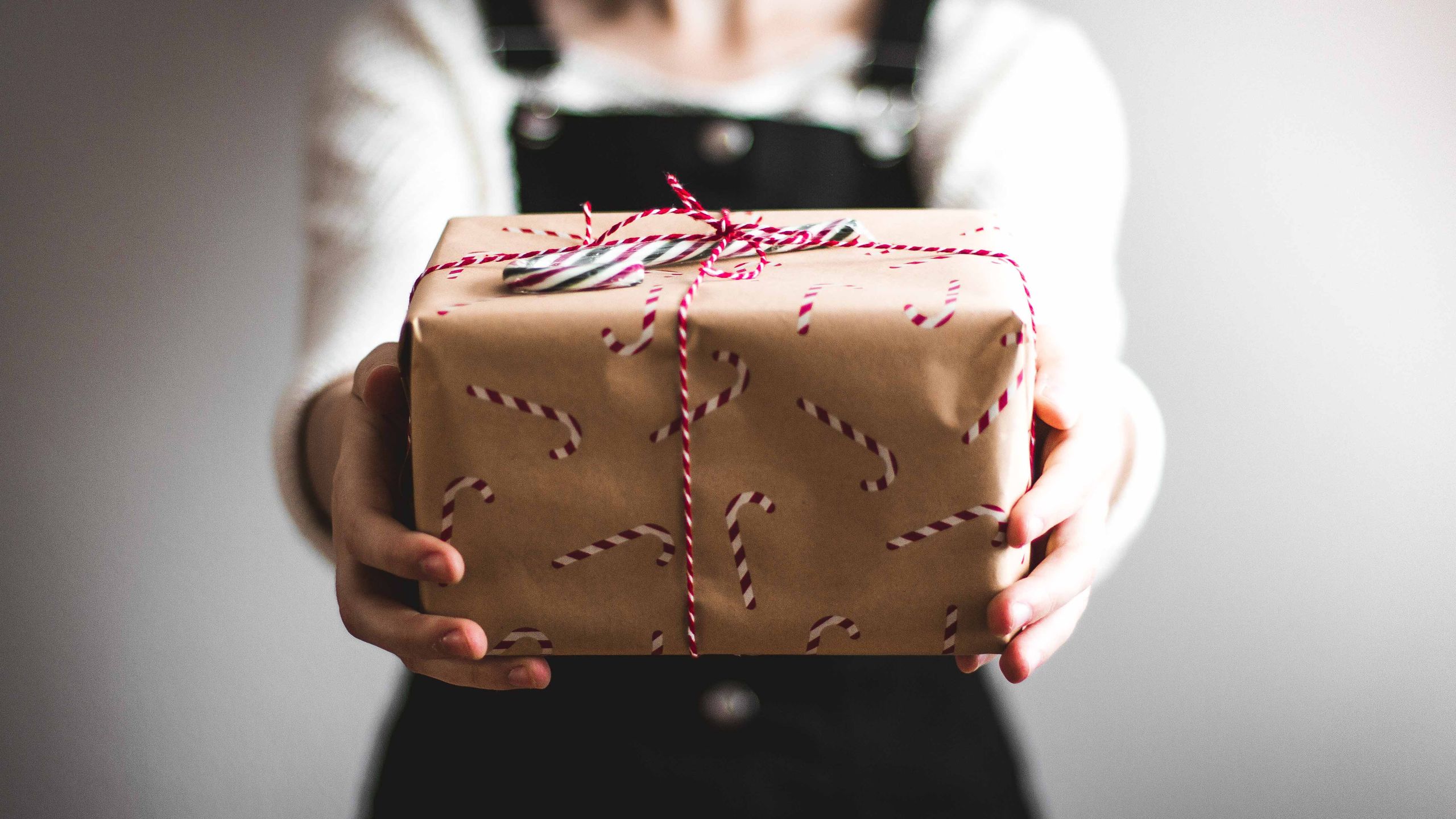 a person holding a holiday-wrapped package with candy canes