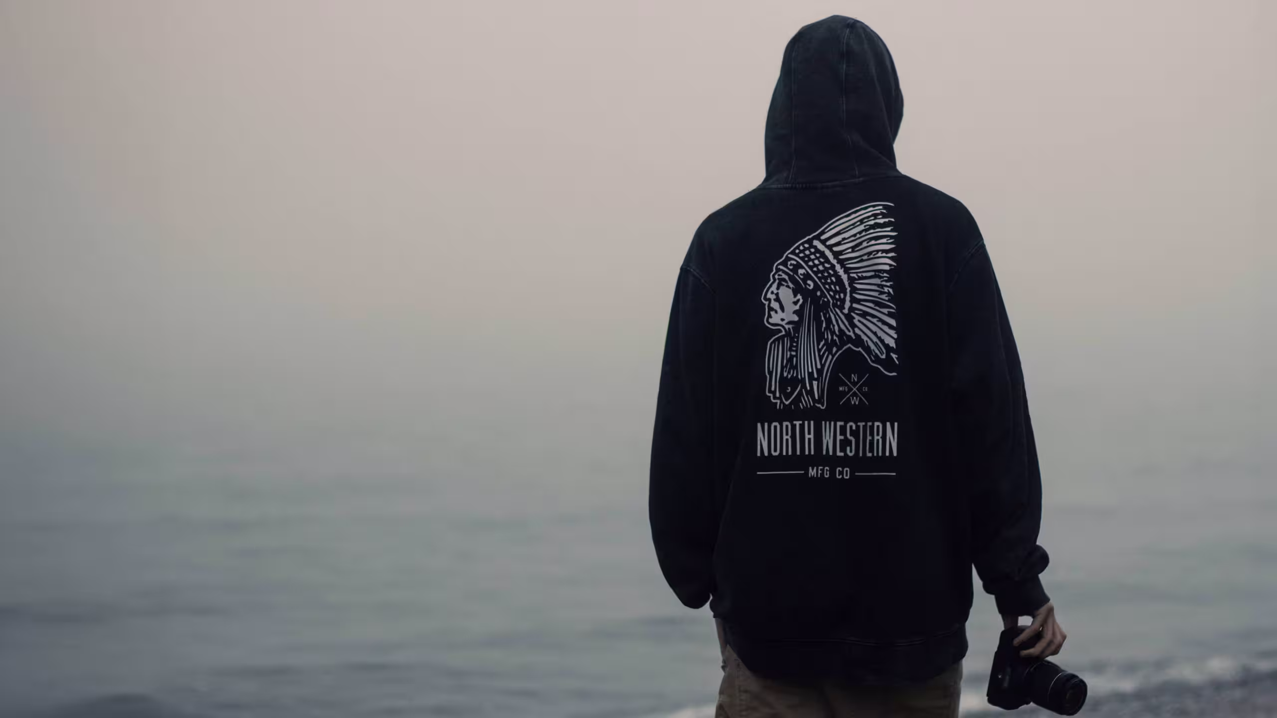 the back of someone wearing a black hoodie holding a camera