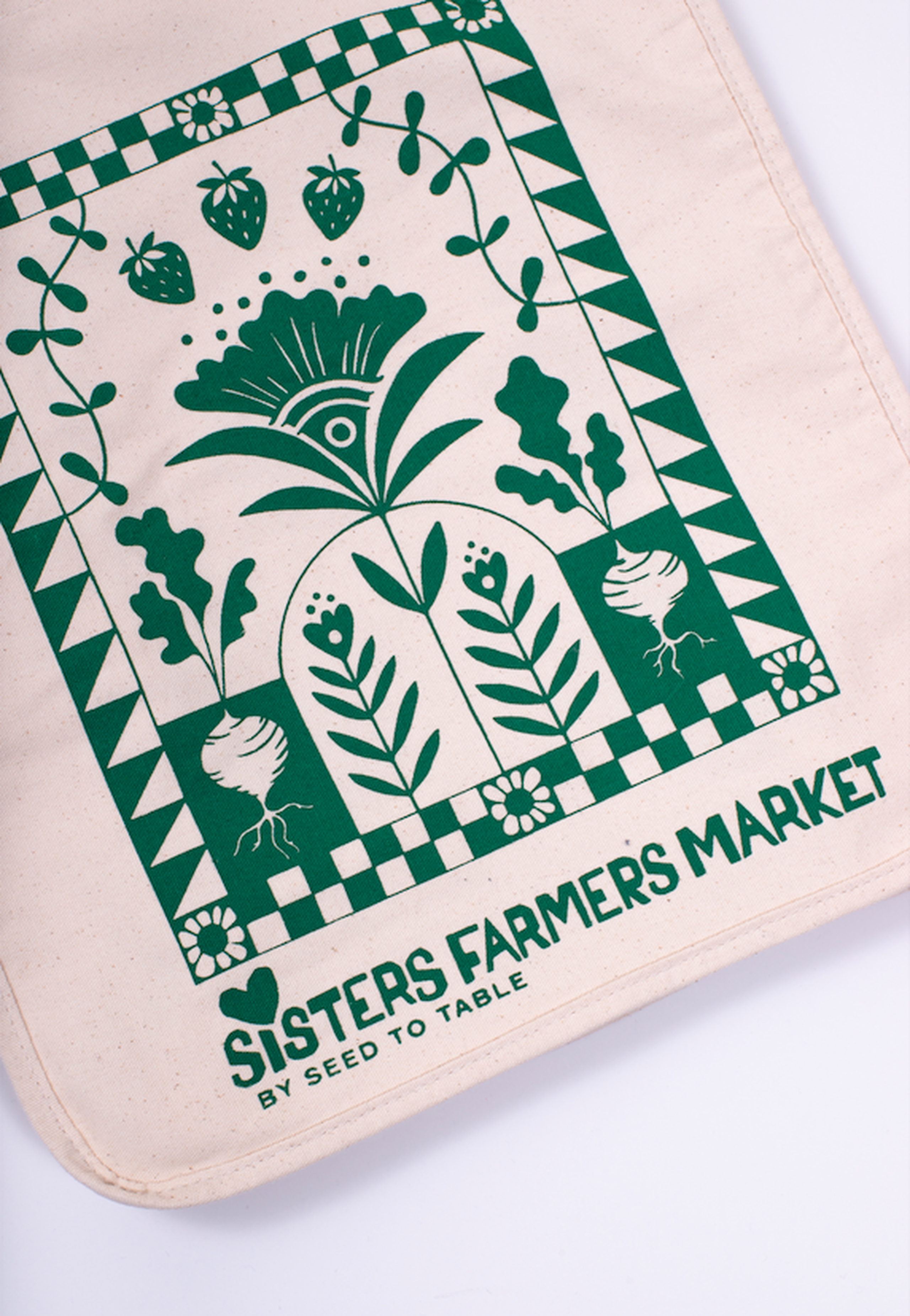 a tote bag printed with green ink with an earthy design and text that says "Sisters Farmers Market"