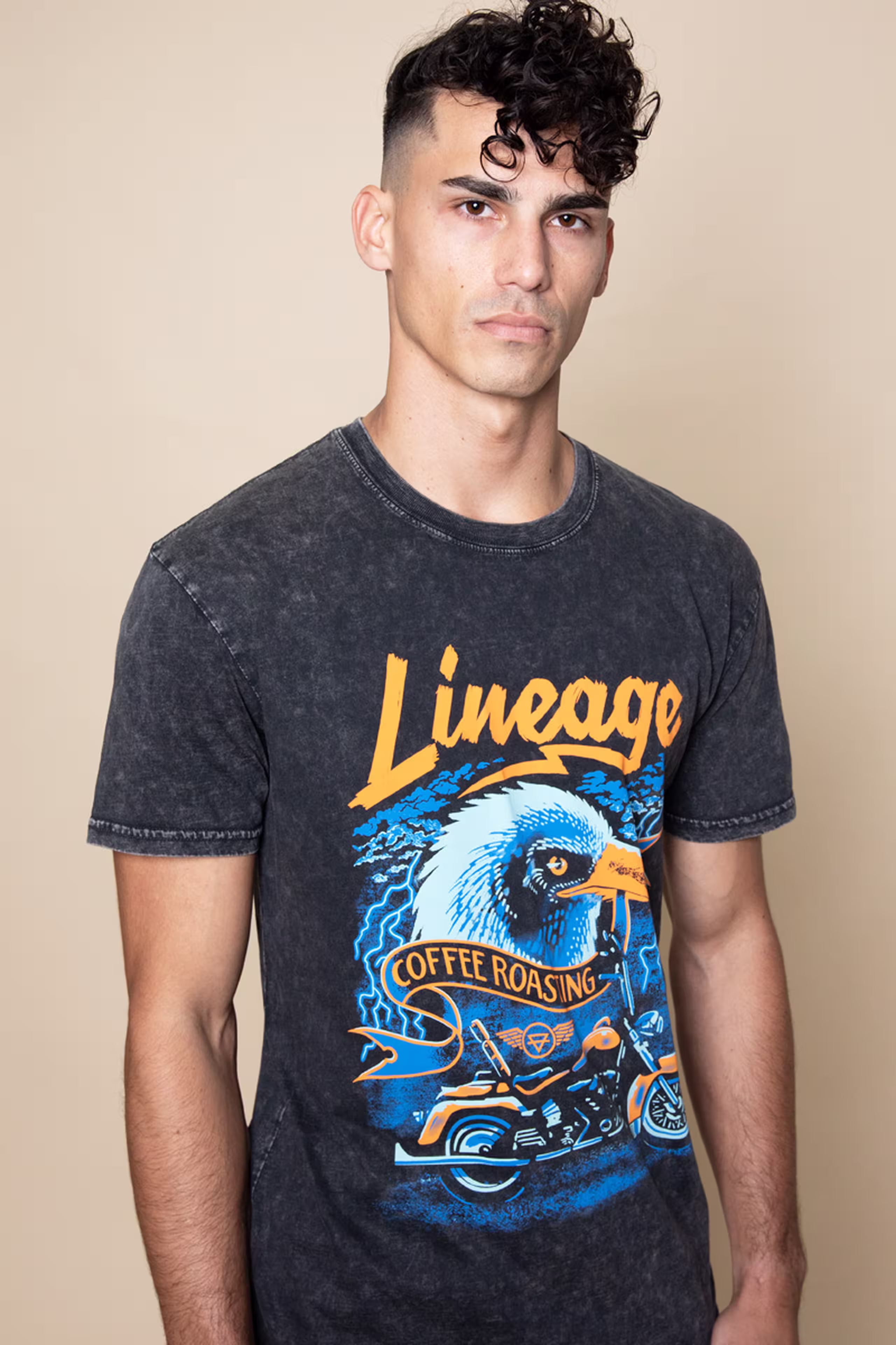 man wearing a black stone wash t-shirt with bright orange "lineage" word and an eagle illustration