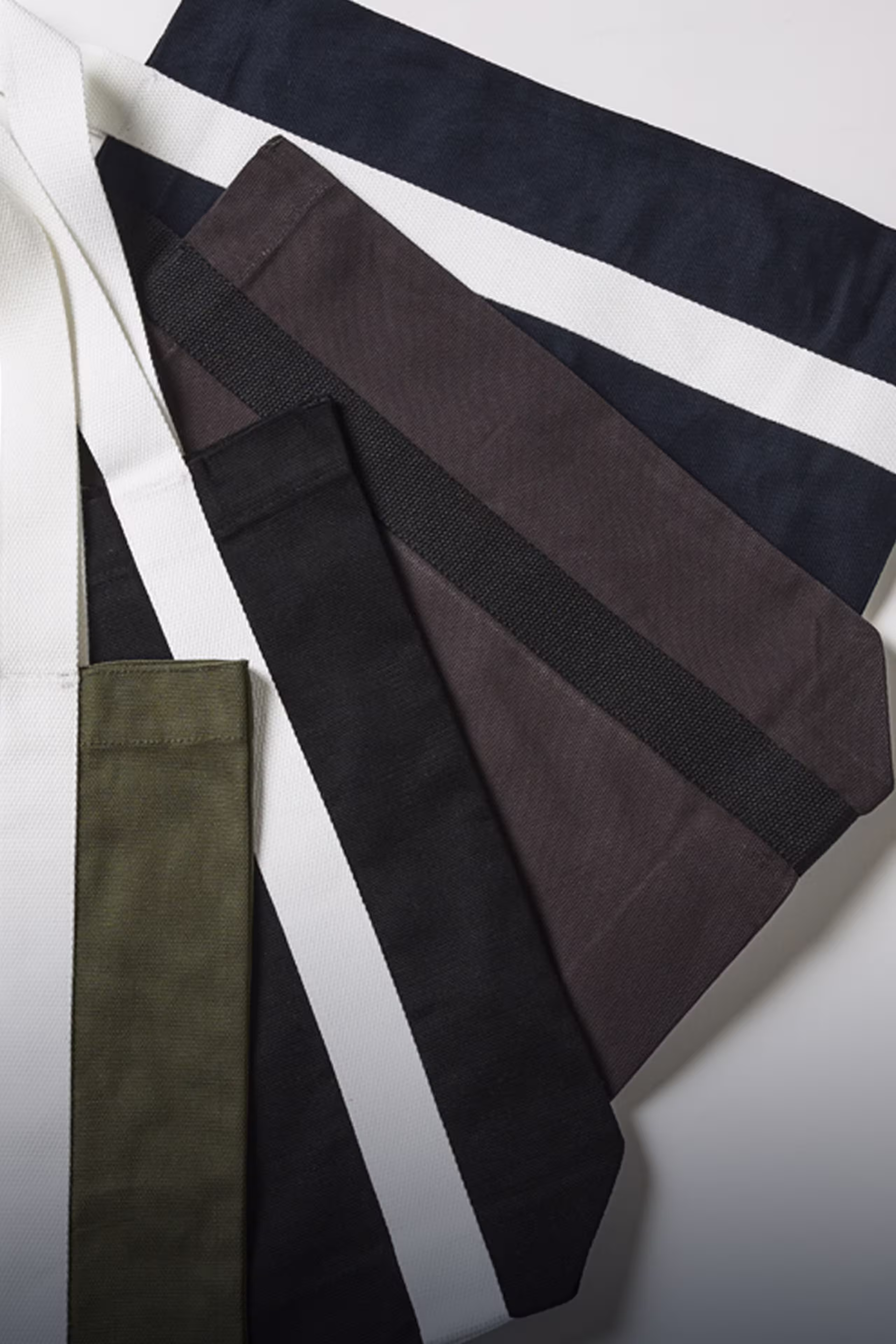 Tote bags lying flat in a fan on top of each other