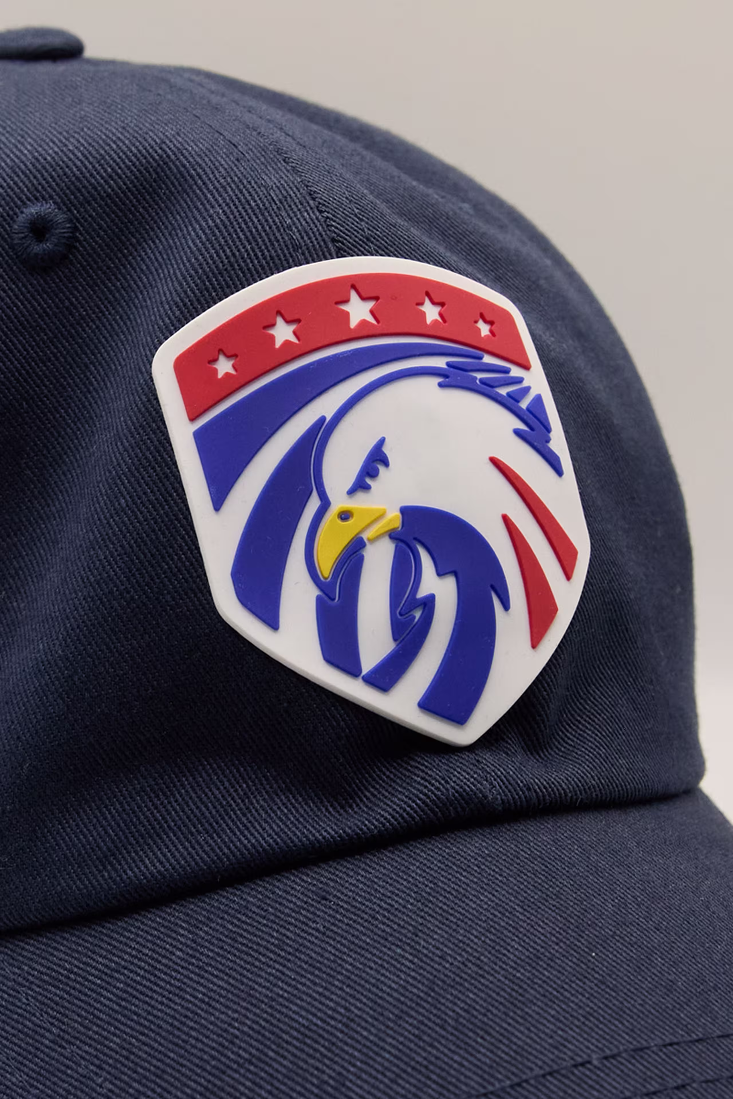 a blue, white, and red eagle in a shield shape molded patch on a navy hat
